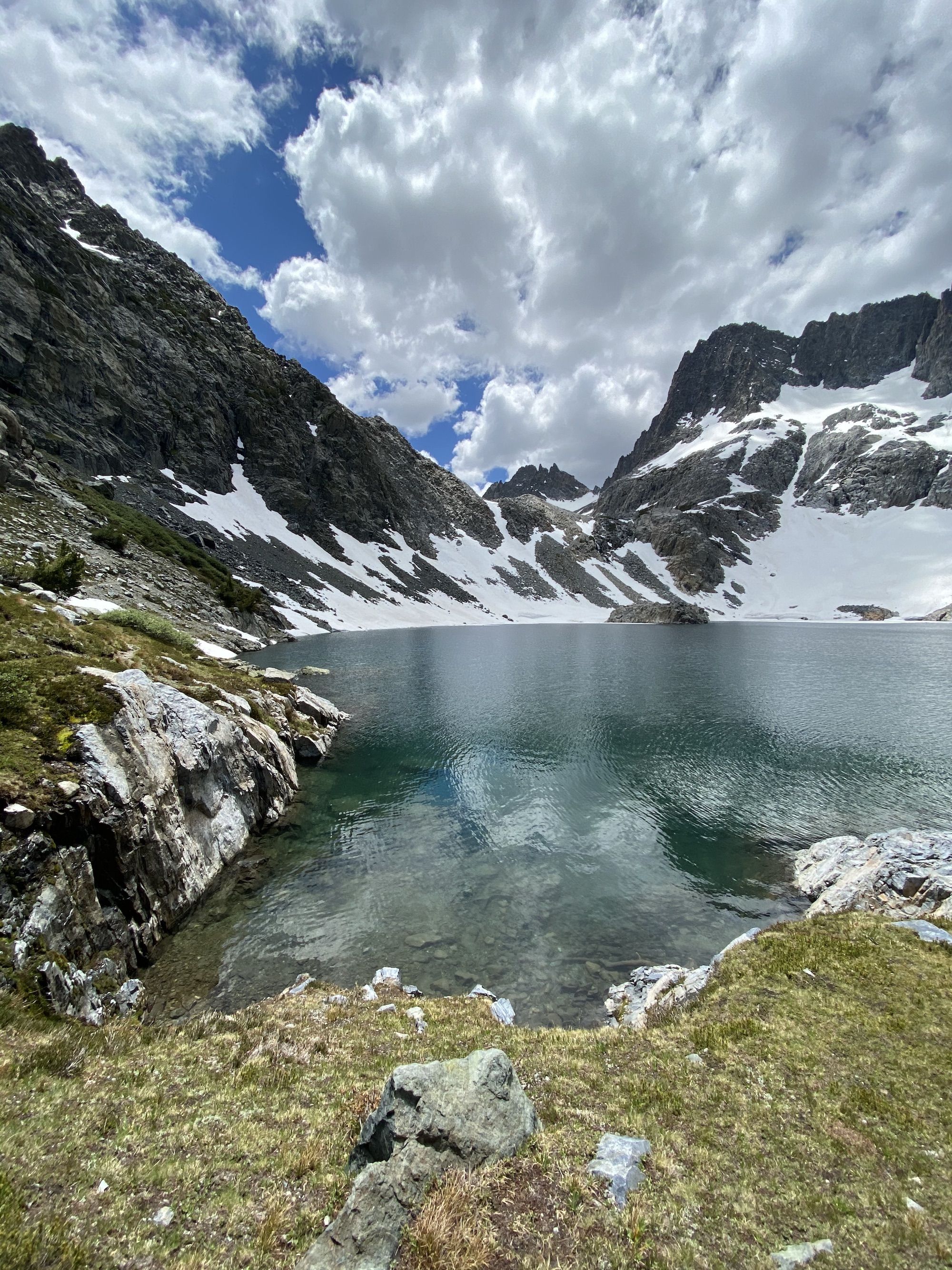 A lake surrounded by high mountains and snow 