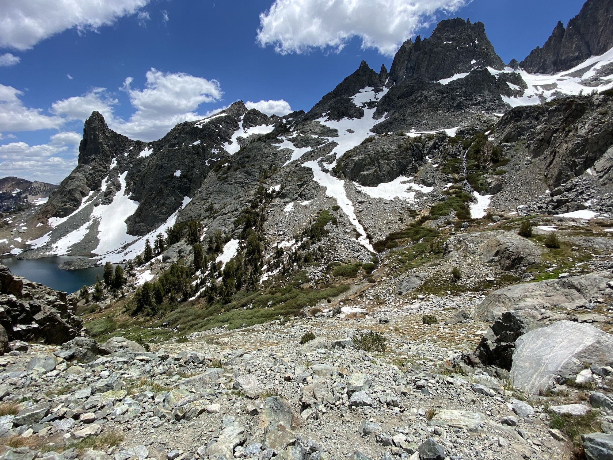 A lake in the distance. A steep rocky descent to the lake. 