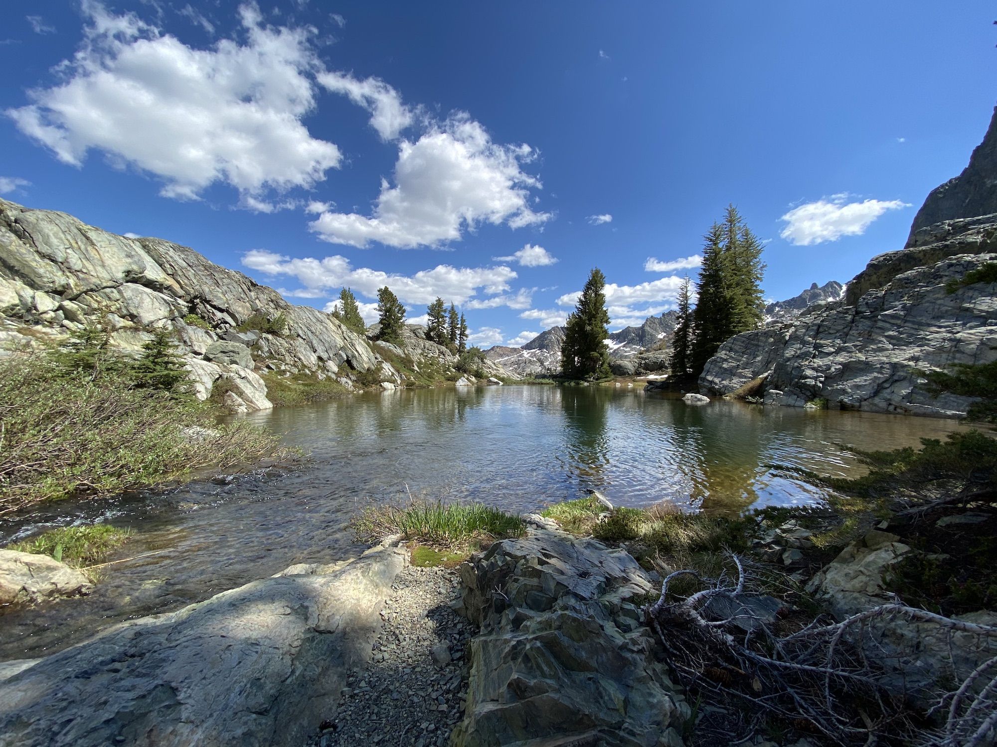 A small stream flowing out into a small lake. 