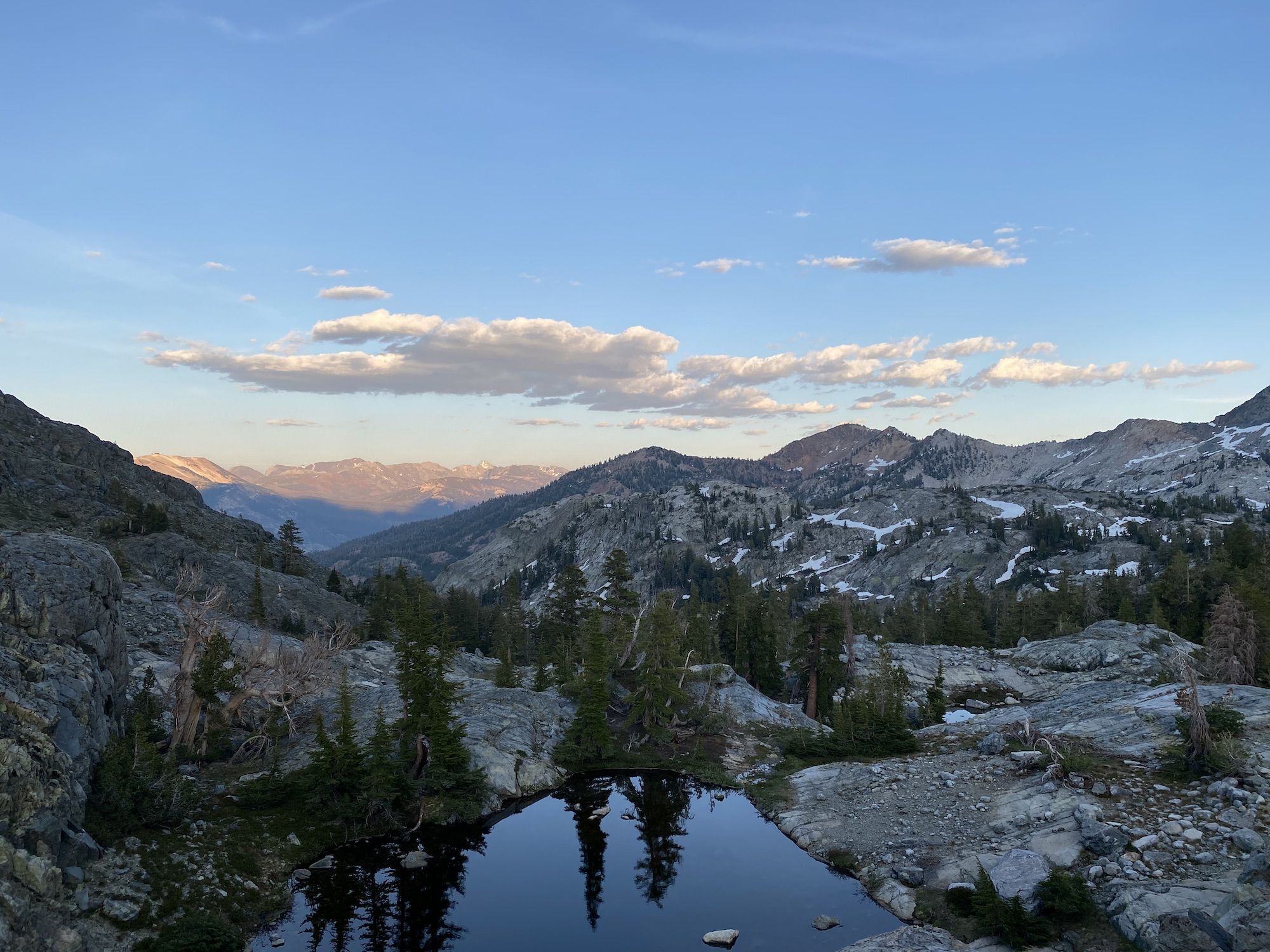 The sun hitting remote mountain peaks, while the closer peaks are already in the shade