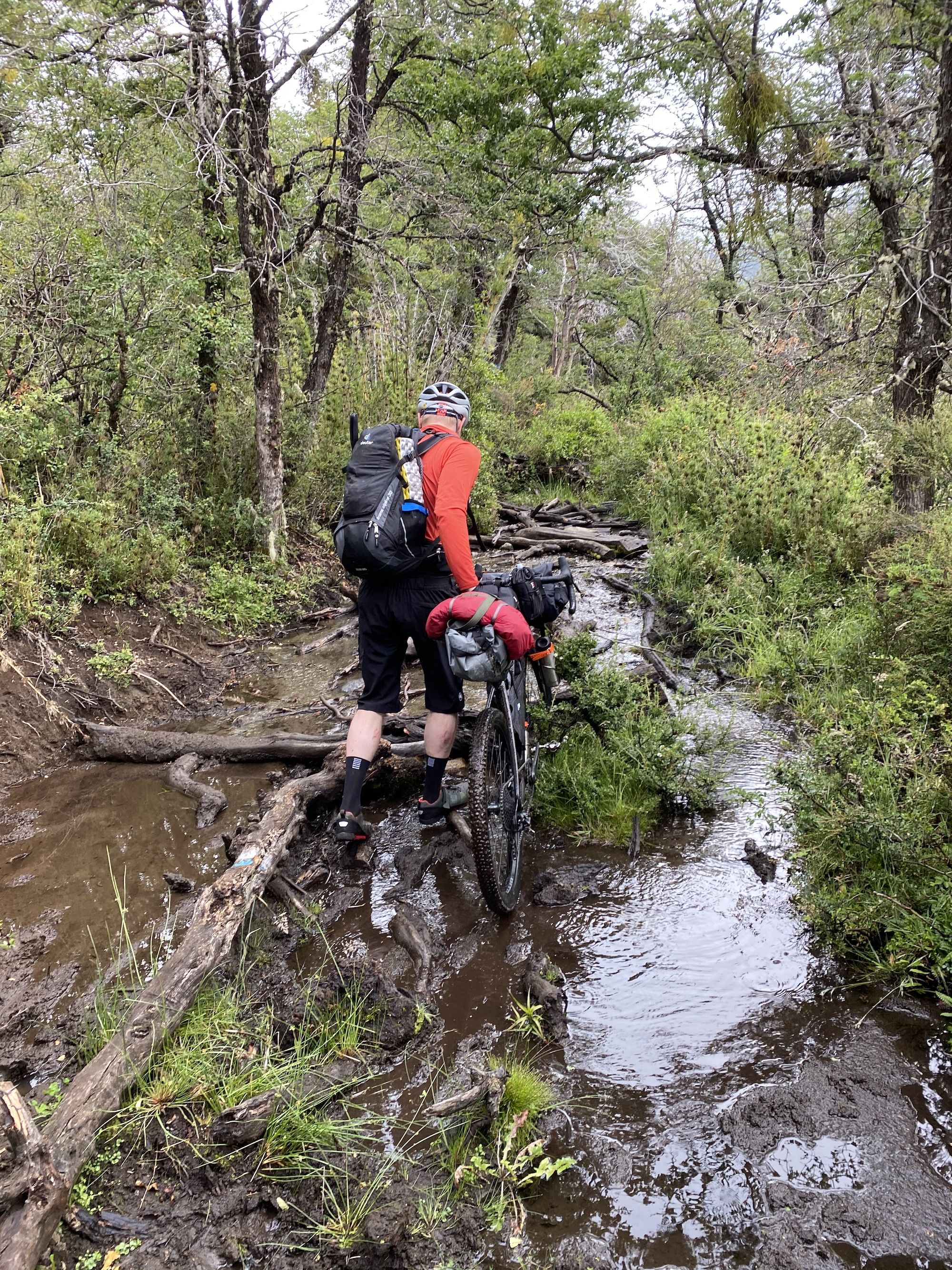 Man pushing his bike through mud on logs