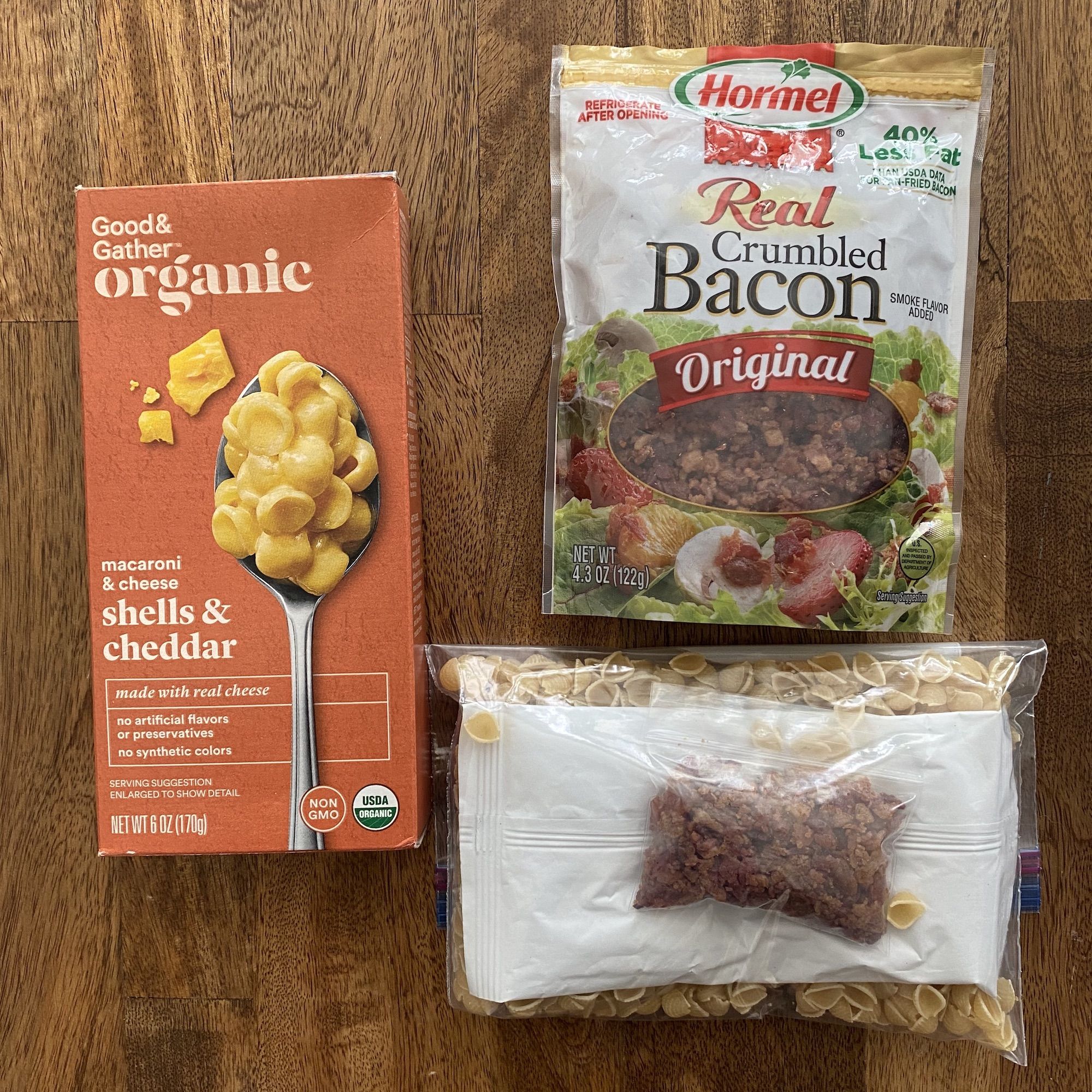 A box of mac and cheese, a bag of bacon crumbles and a Ziplock bag with the prepared meal.