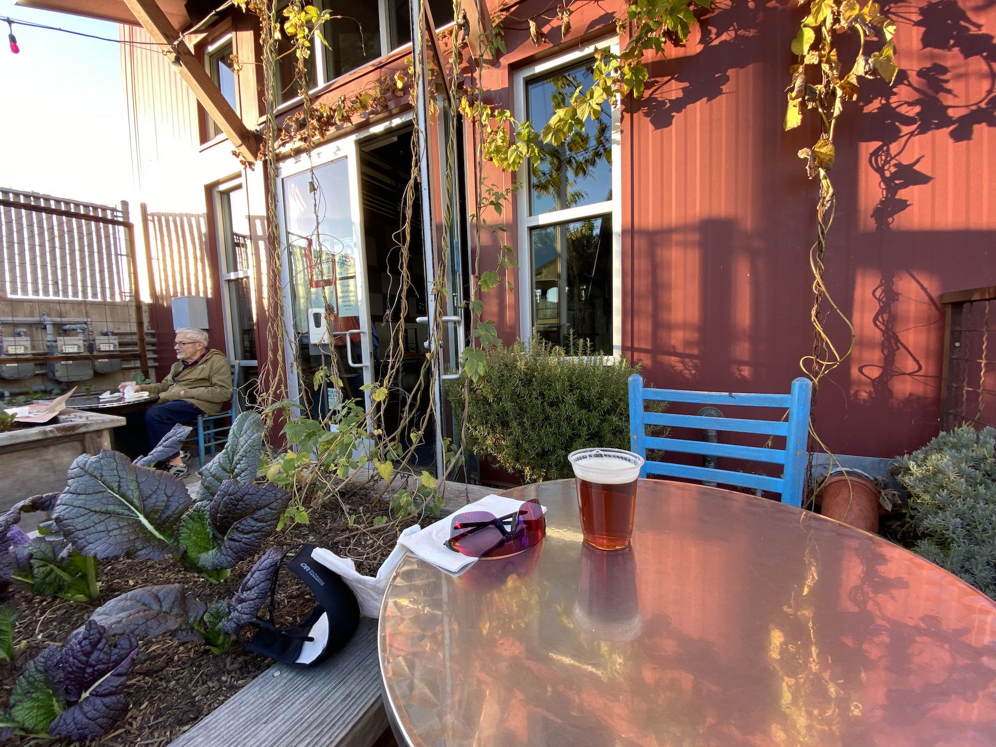 A beer glass, mask, and sun glasses on a table. 