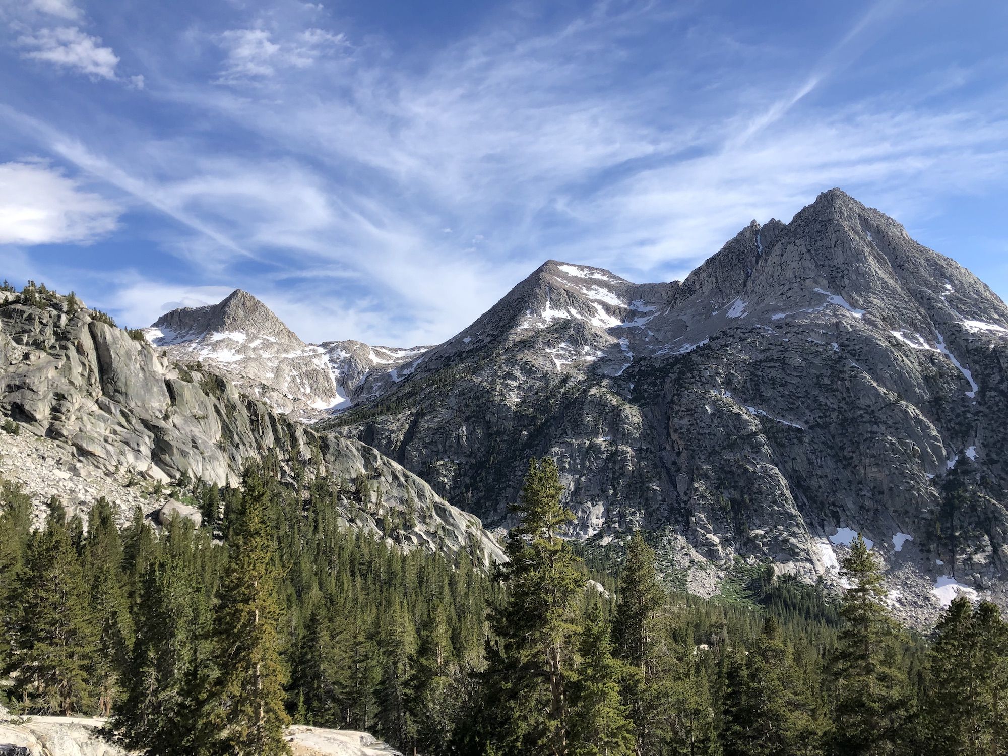 A mountain landscape with trees below and bare granite mountain sides above