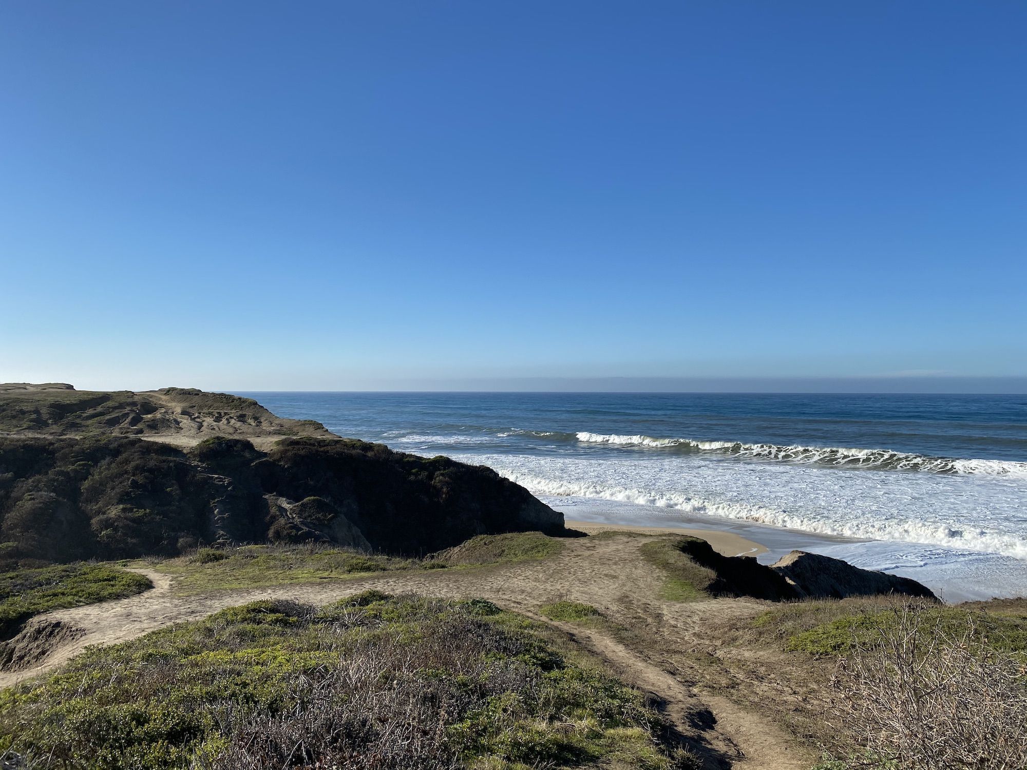 Waves rolling onto a beach beneath cliffs