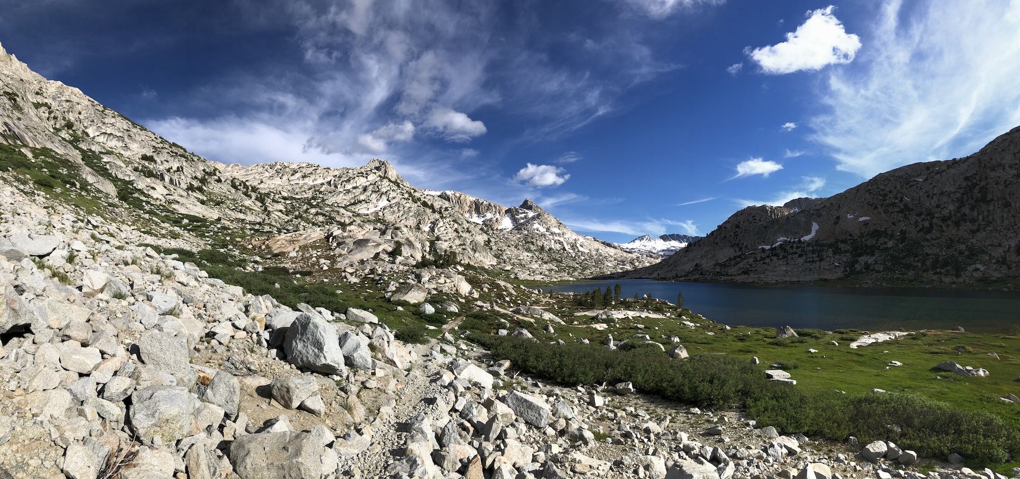 A view of the trail on the left side of Evolution Lake with mountains on both sides.