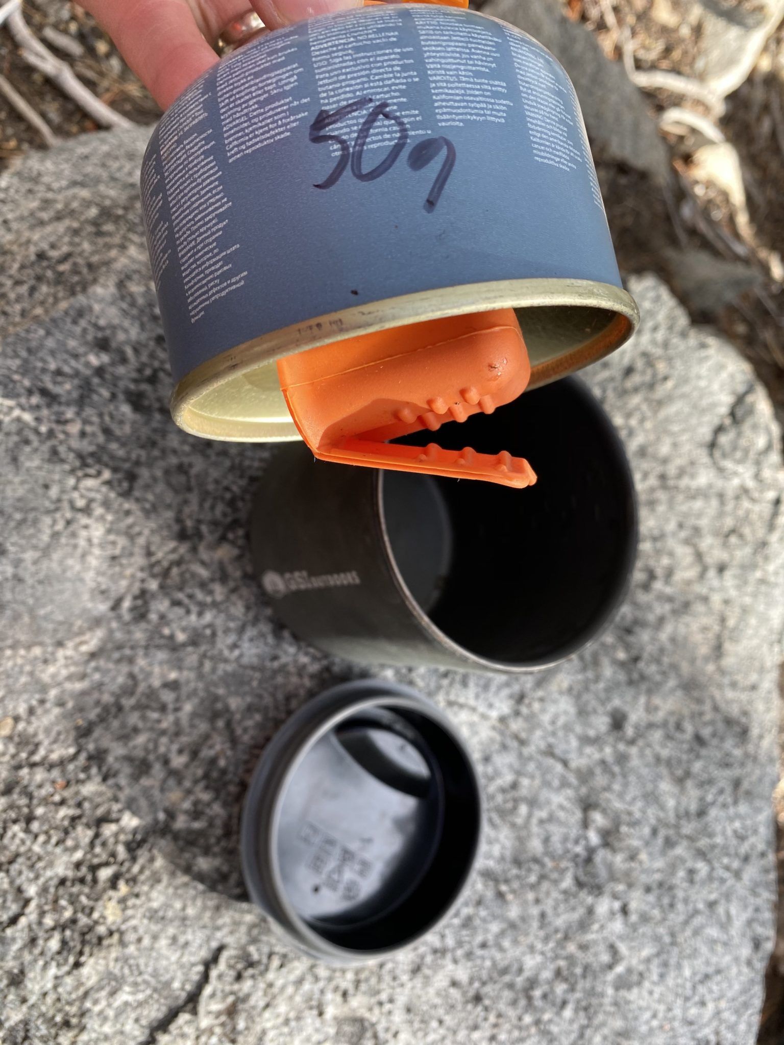 The pot holder is attached to the bottom of the fuel canister with a magnet.