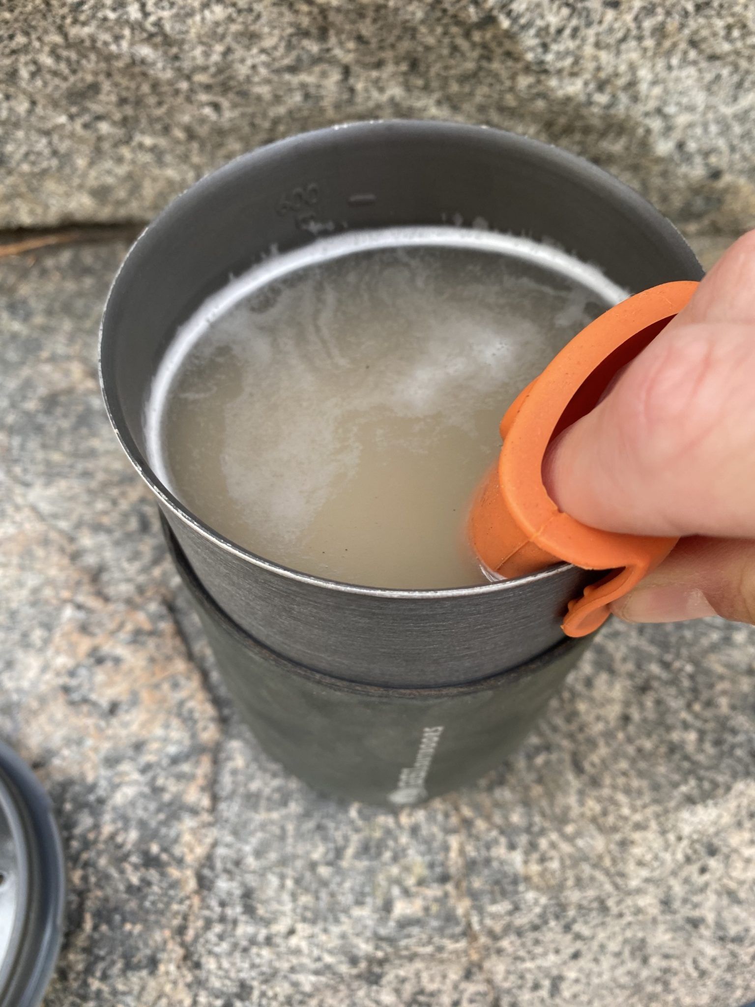 Using the silicone potholder to lift the pot into the sleeve.