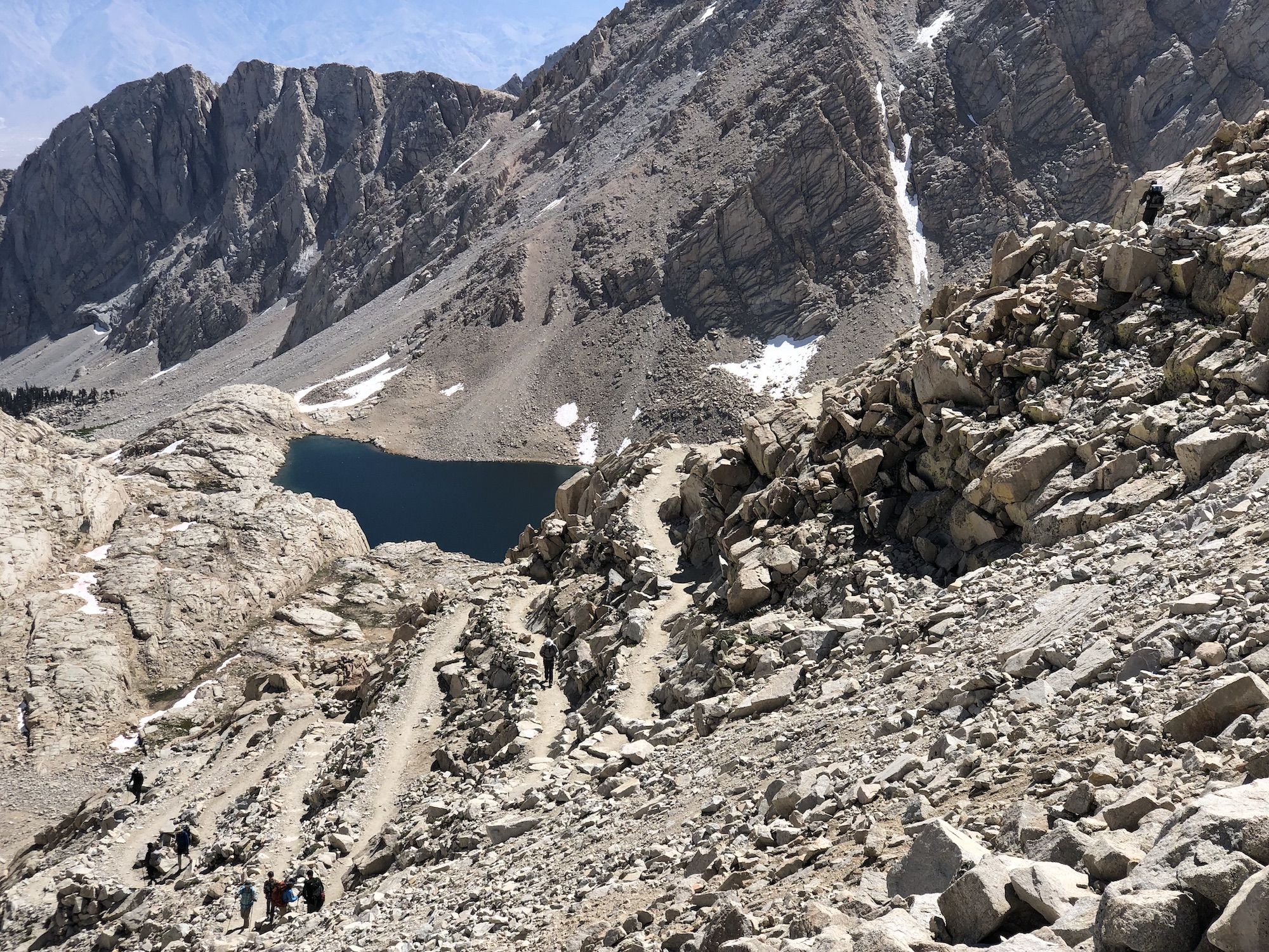 A trail switchbacking down a rocky mountain side.