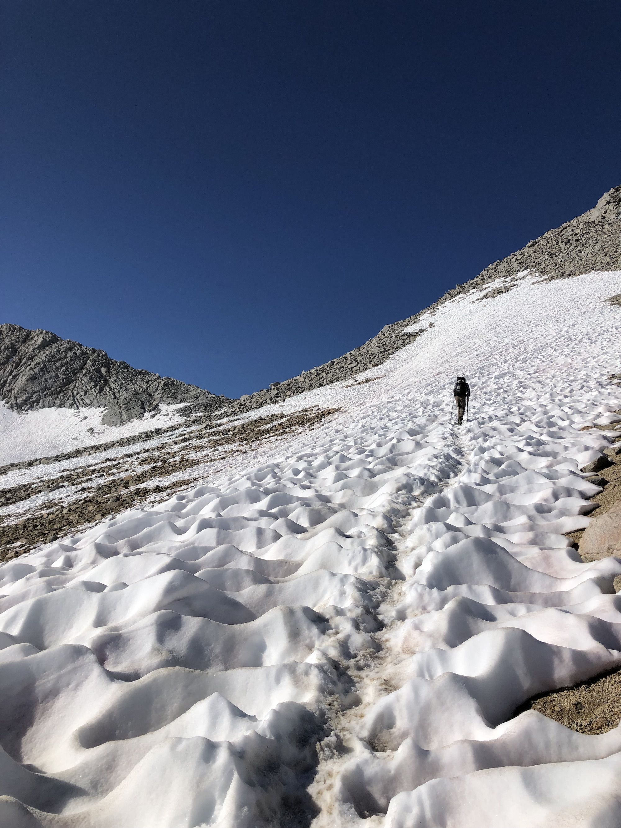 A hiker crossing a snow field