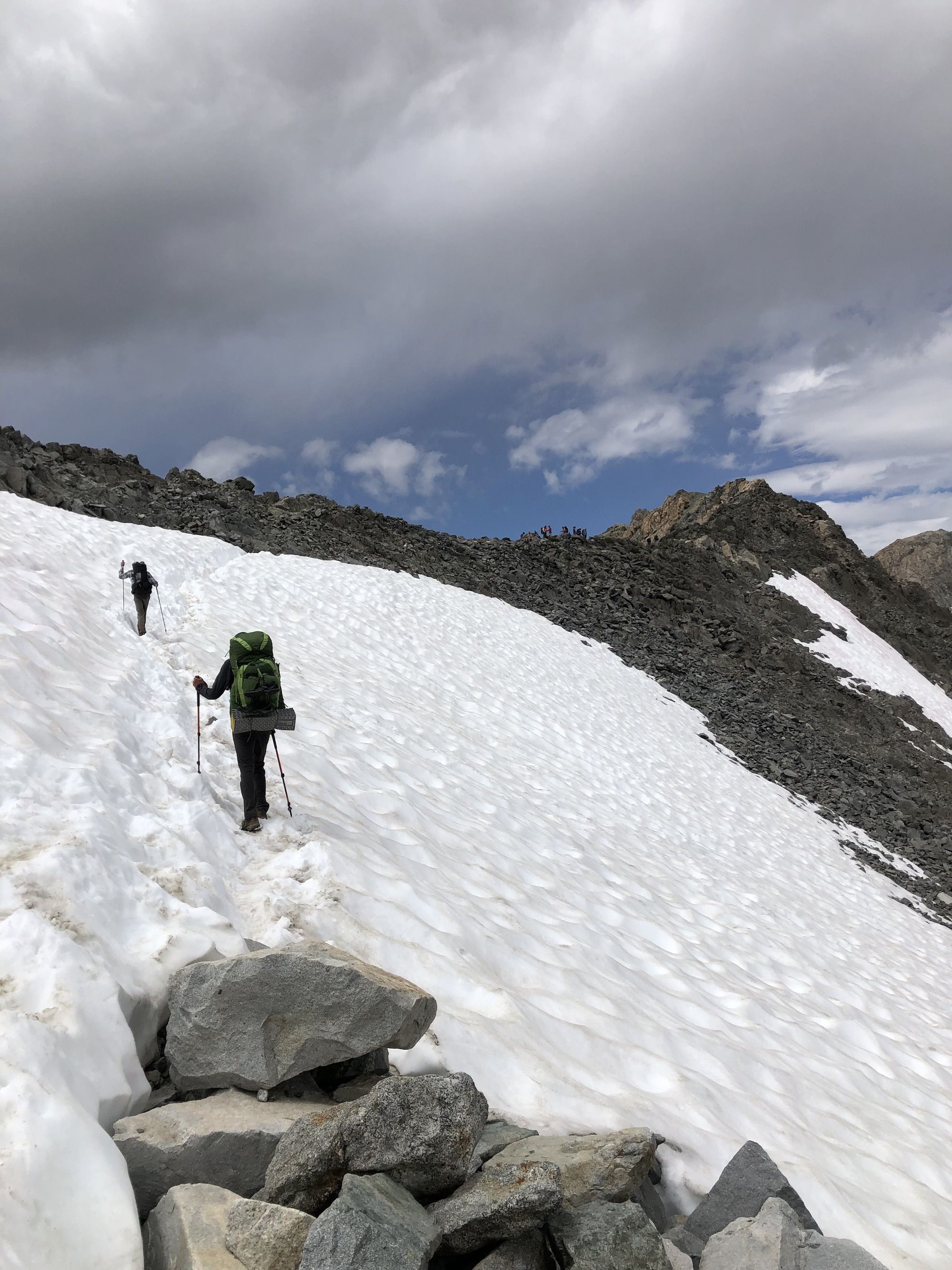 Two hikers crossing an angled snow field