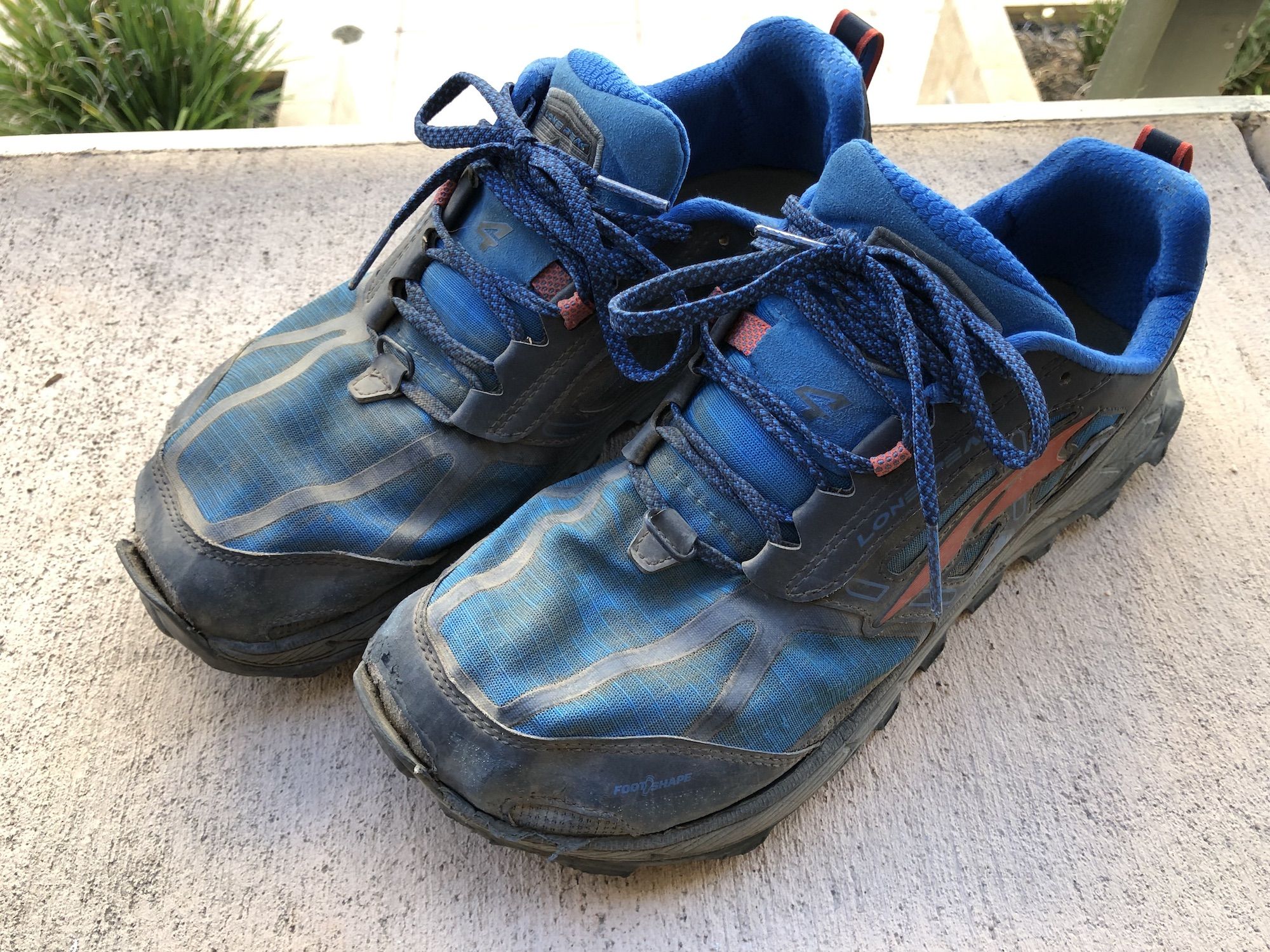 A worn pair of shoes with lose pieces.