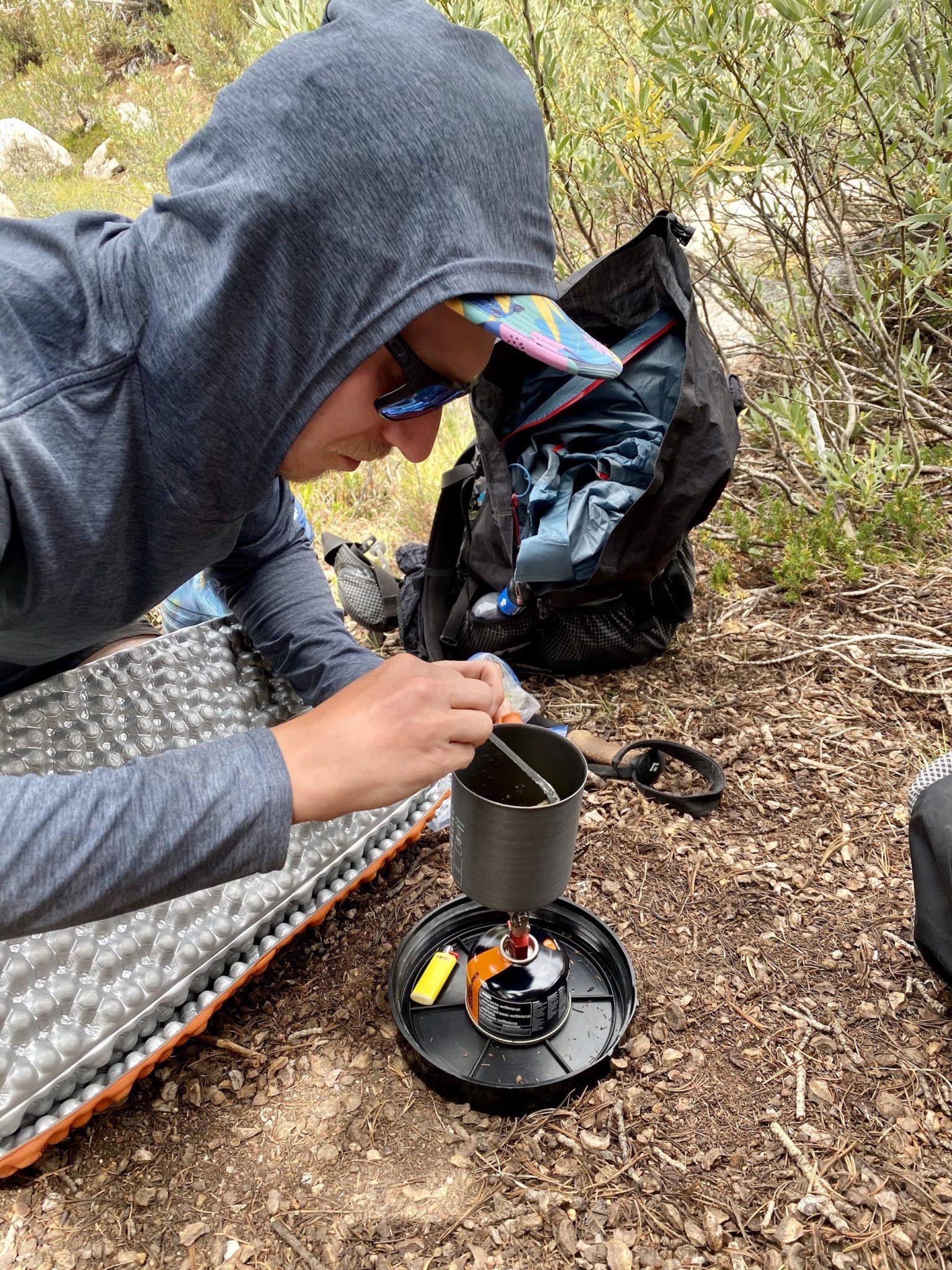 A man cooking fish on a camping stove.