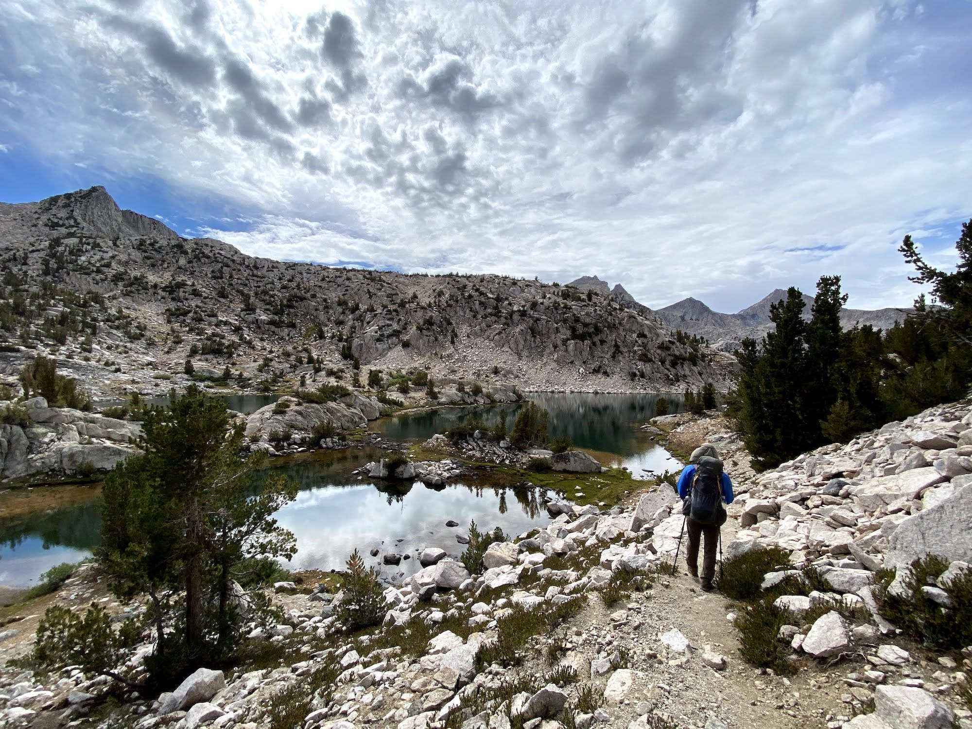 A backpacker walking along two lakes.