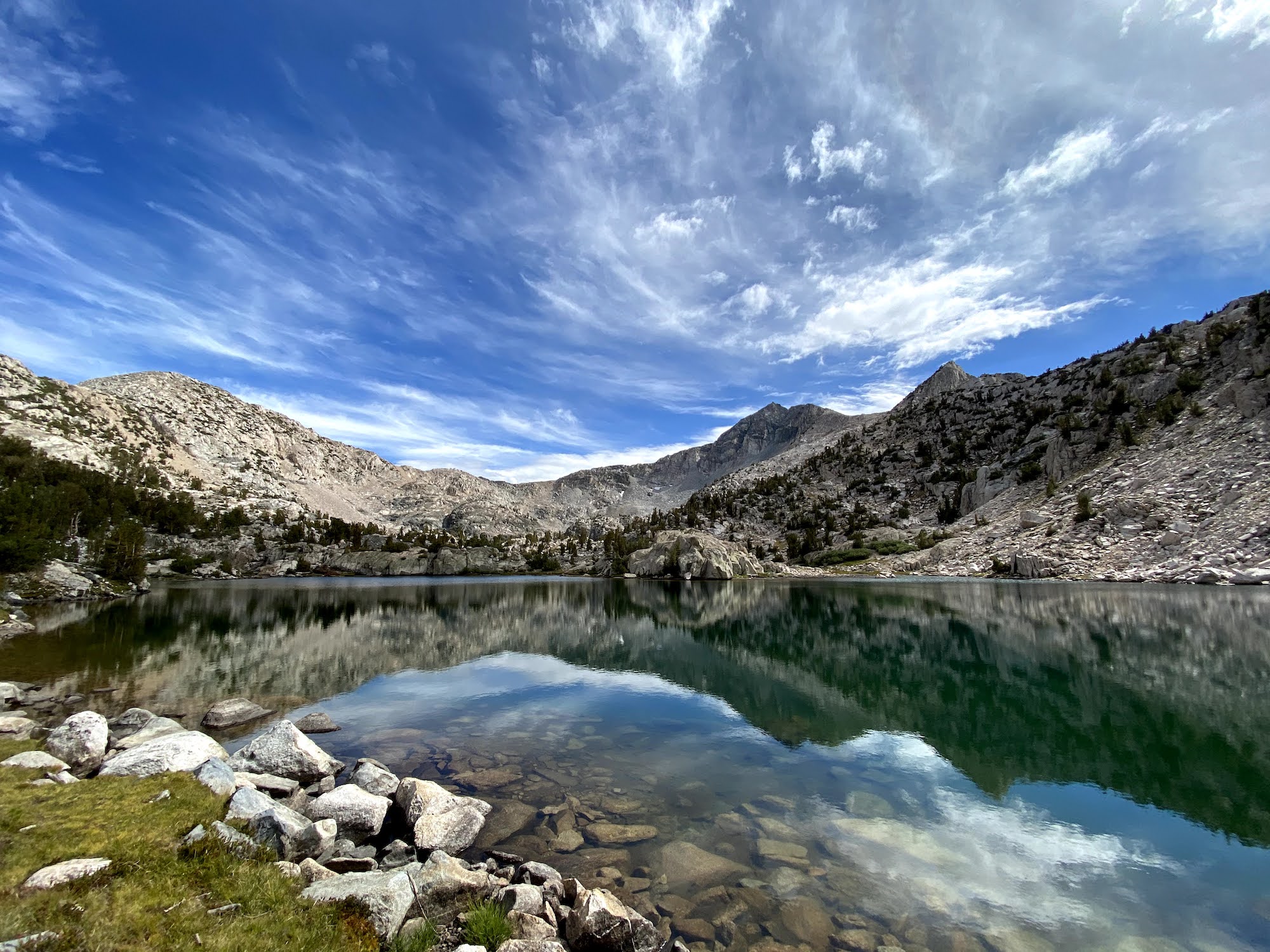 A calm lake reflecting the mountains on the other side. 