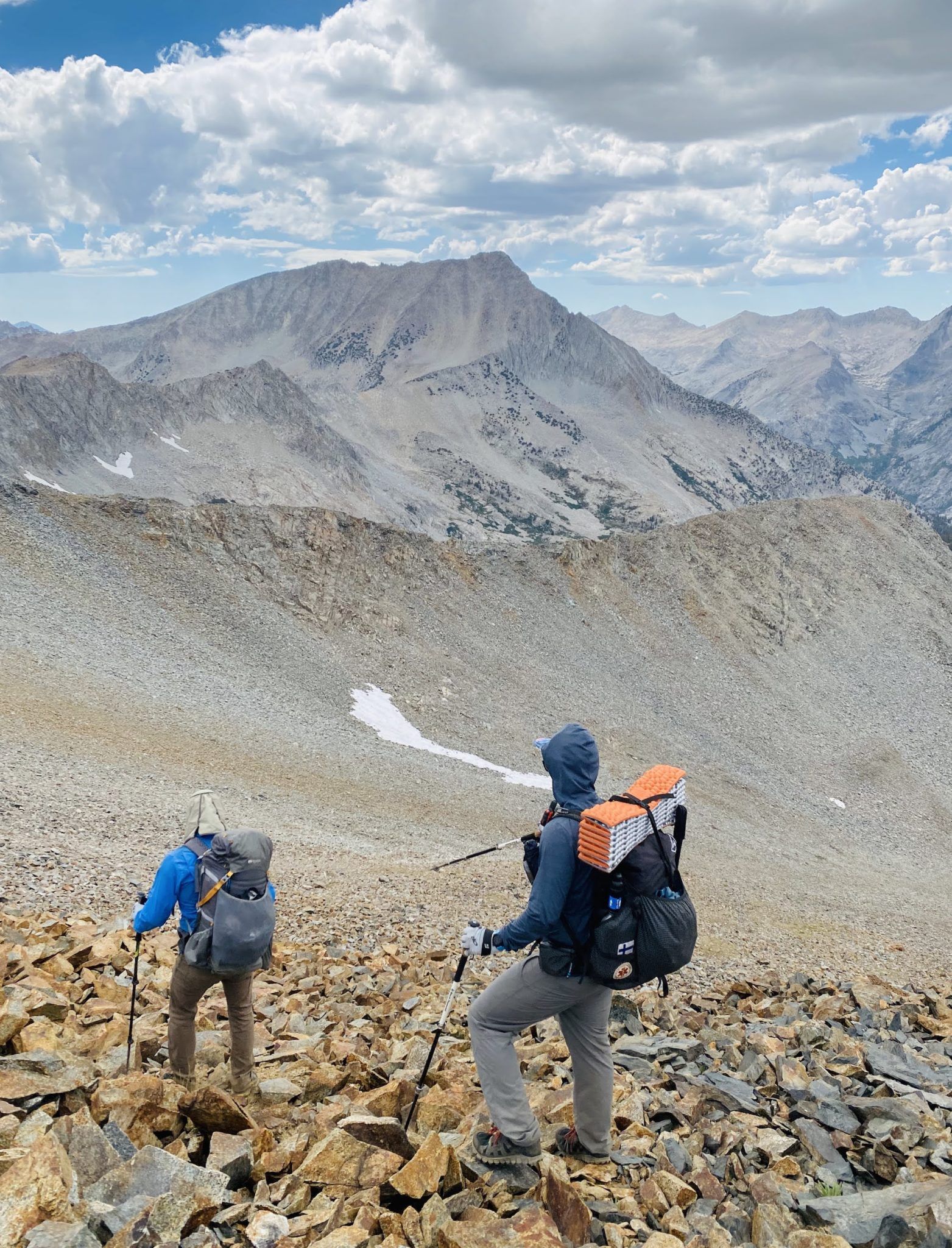 A man pointing down a rock field with a hiking pole