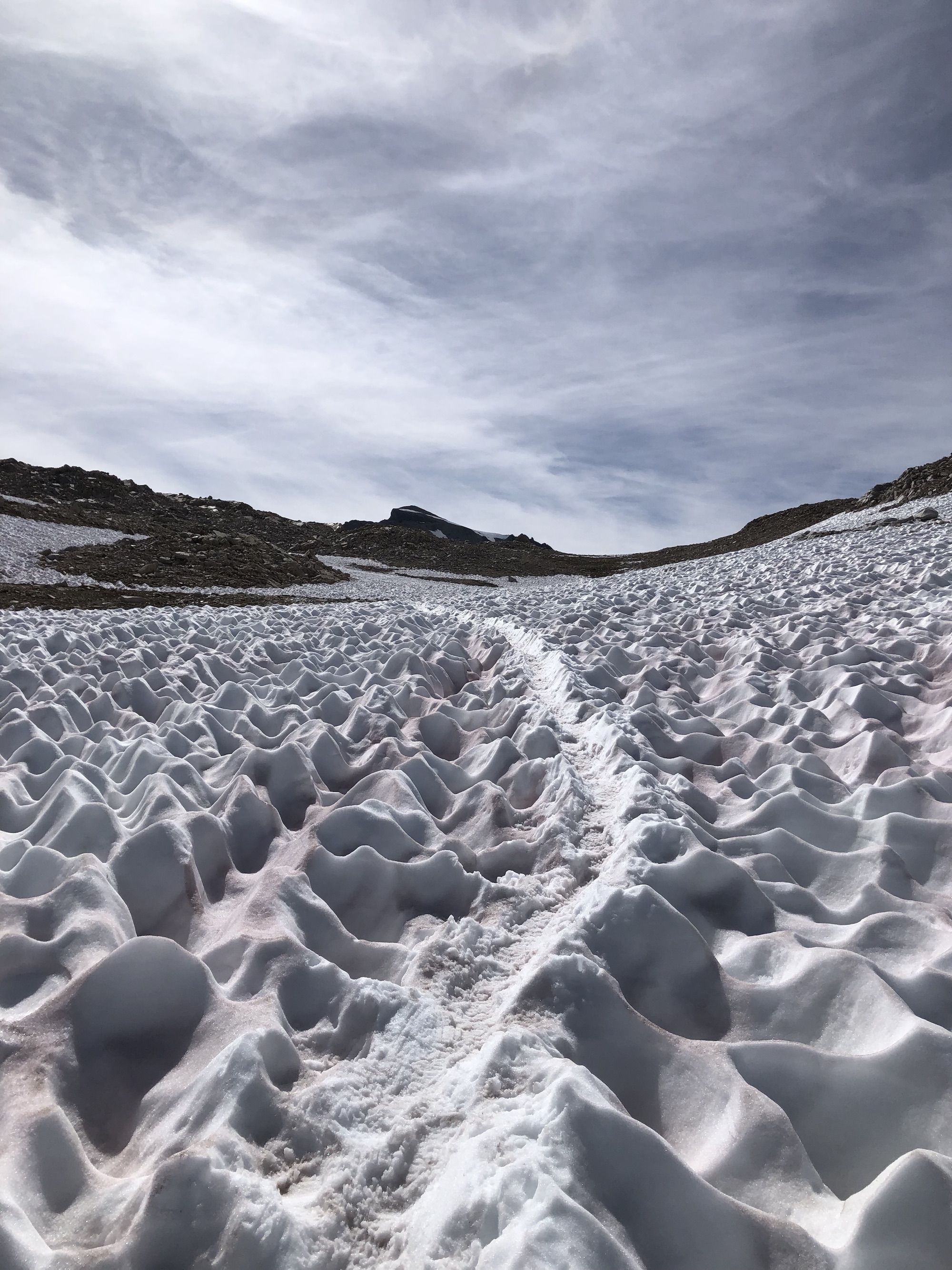 A boot track through a snow field heading uphill