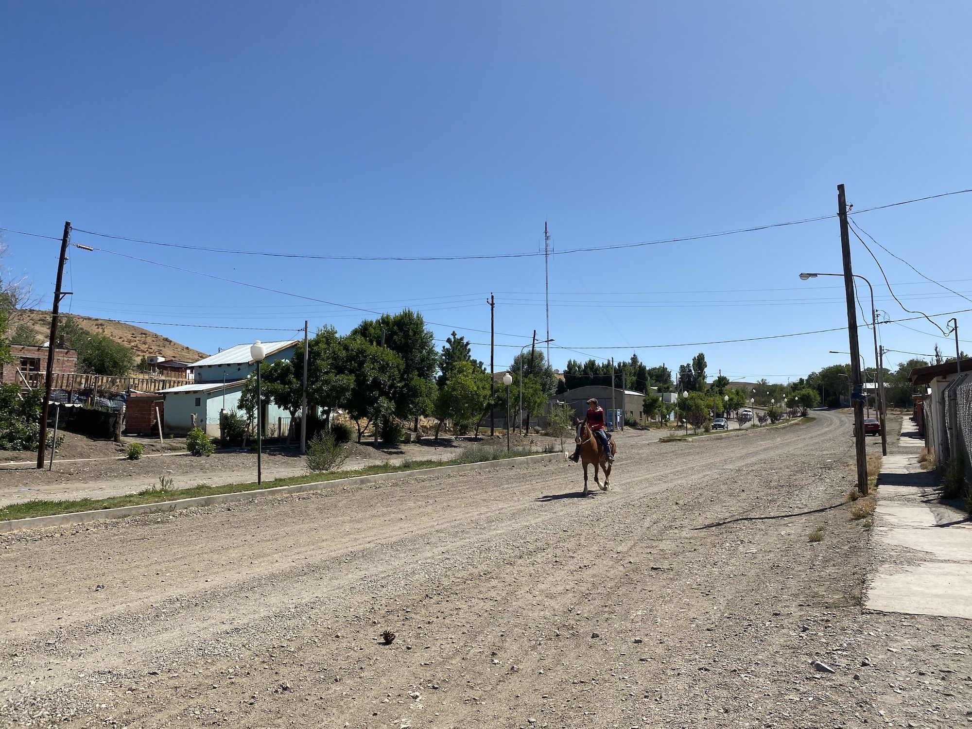 Man riding a horse down a gravel road in a small village in Argentina