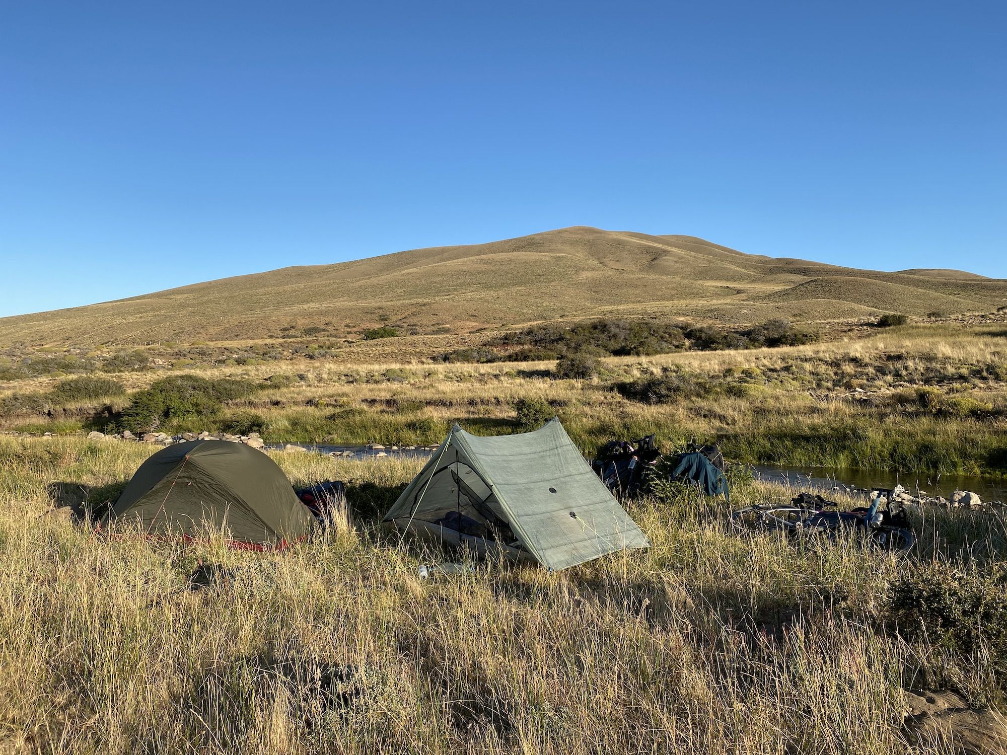 Bikepacking camp in the Patagonian desert. Two tents and bikes next to a river.