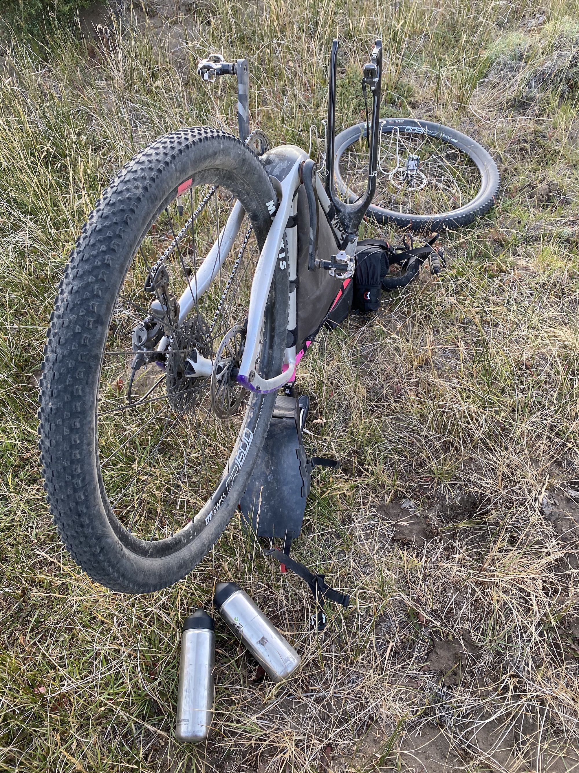 Bike upside down in tall grass. The front wheel is off. 
