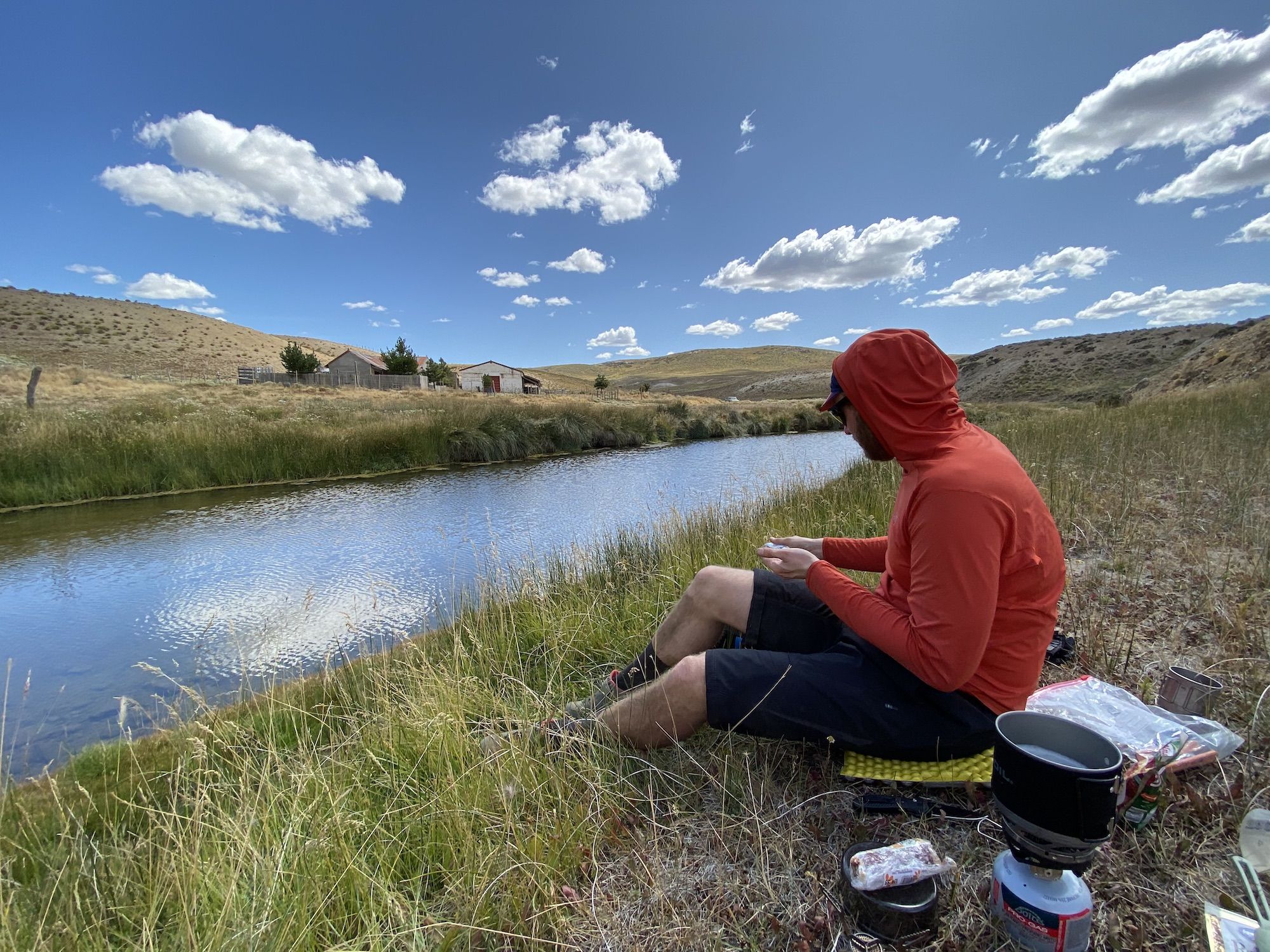 Man sitting on the riverbank with a camping stove