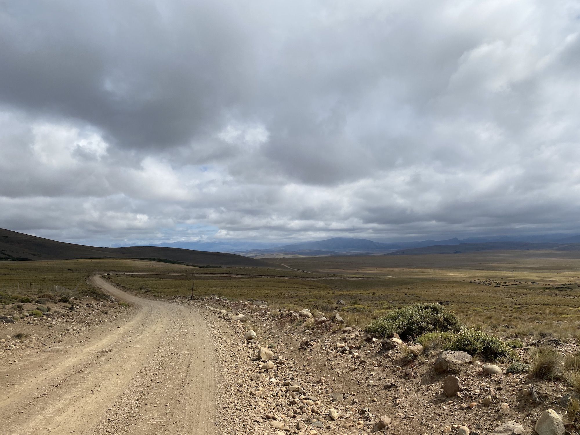 A long gravel road under a dark cloudy sky