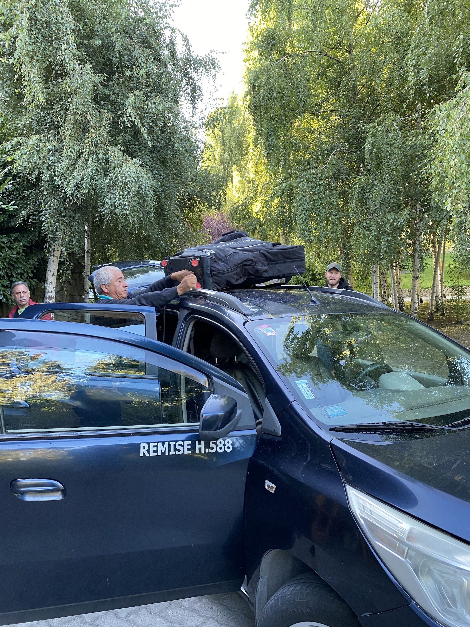 A man strapping a bike box to the top of a car