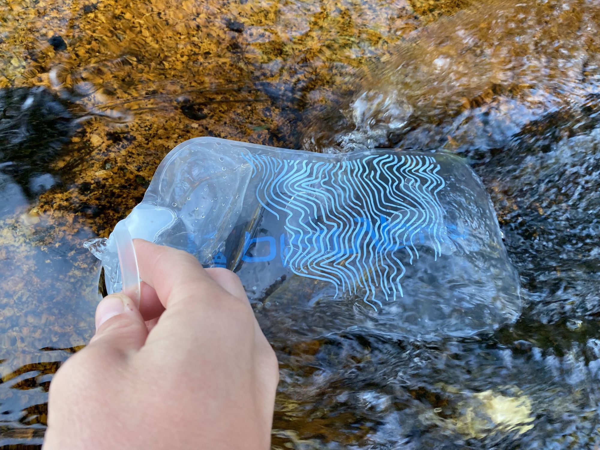 Reviewing the Platypus QuickDraw bag water scooping qualities by filling it with water from a stream.