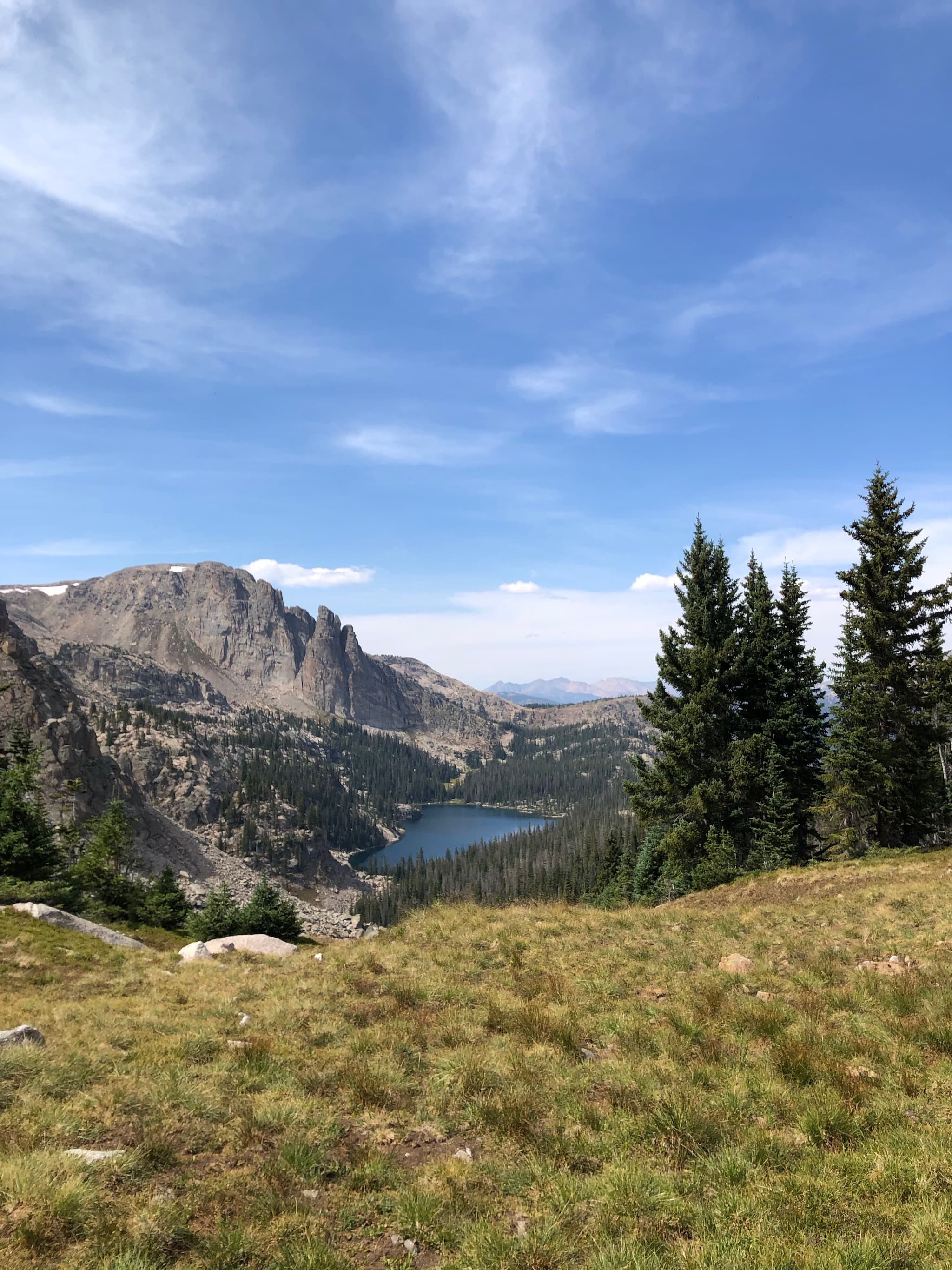 A lake surrounded by tall mountains and trees.