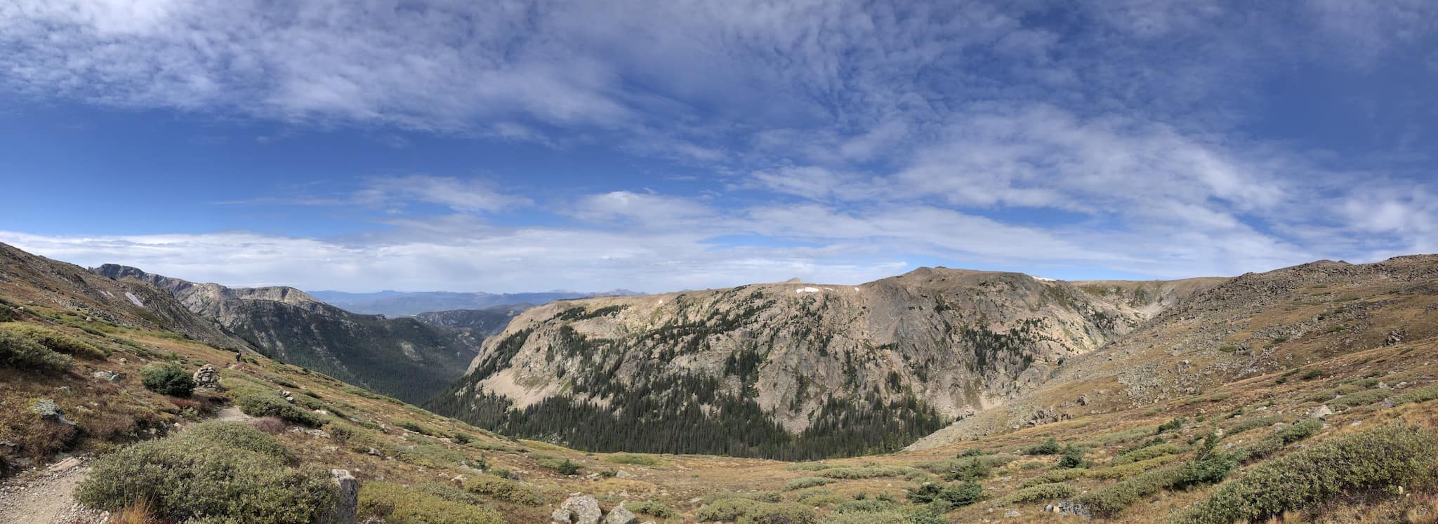 A wide view of a valley with bare mountain tops and forest in the valley.