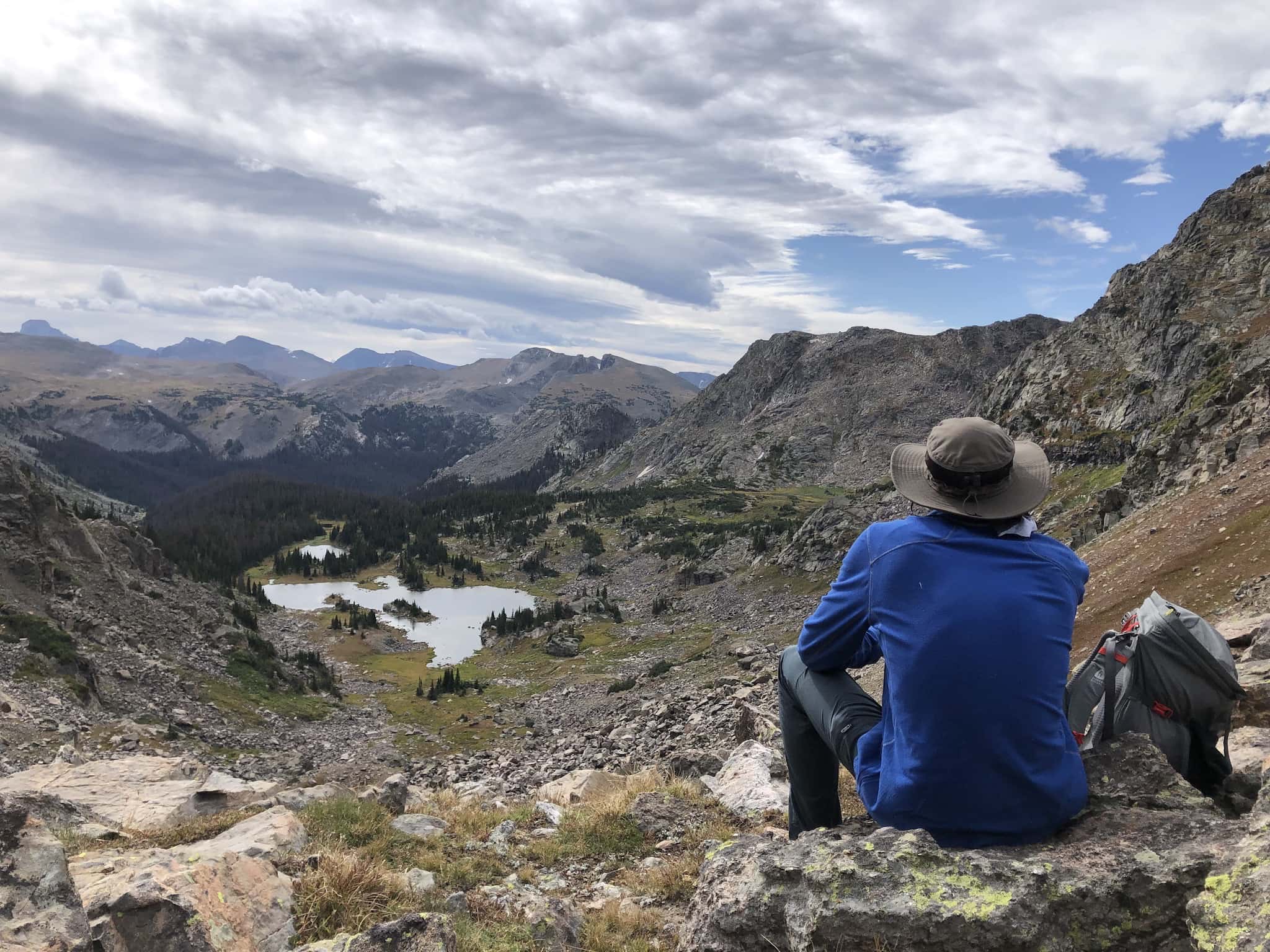 A man sitting on a rock, looking down at a valley.