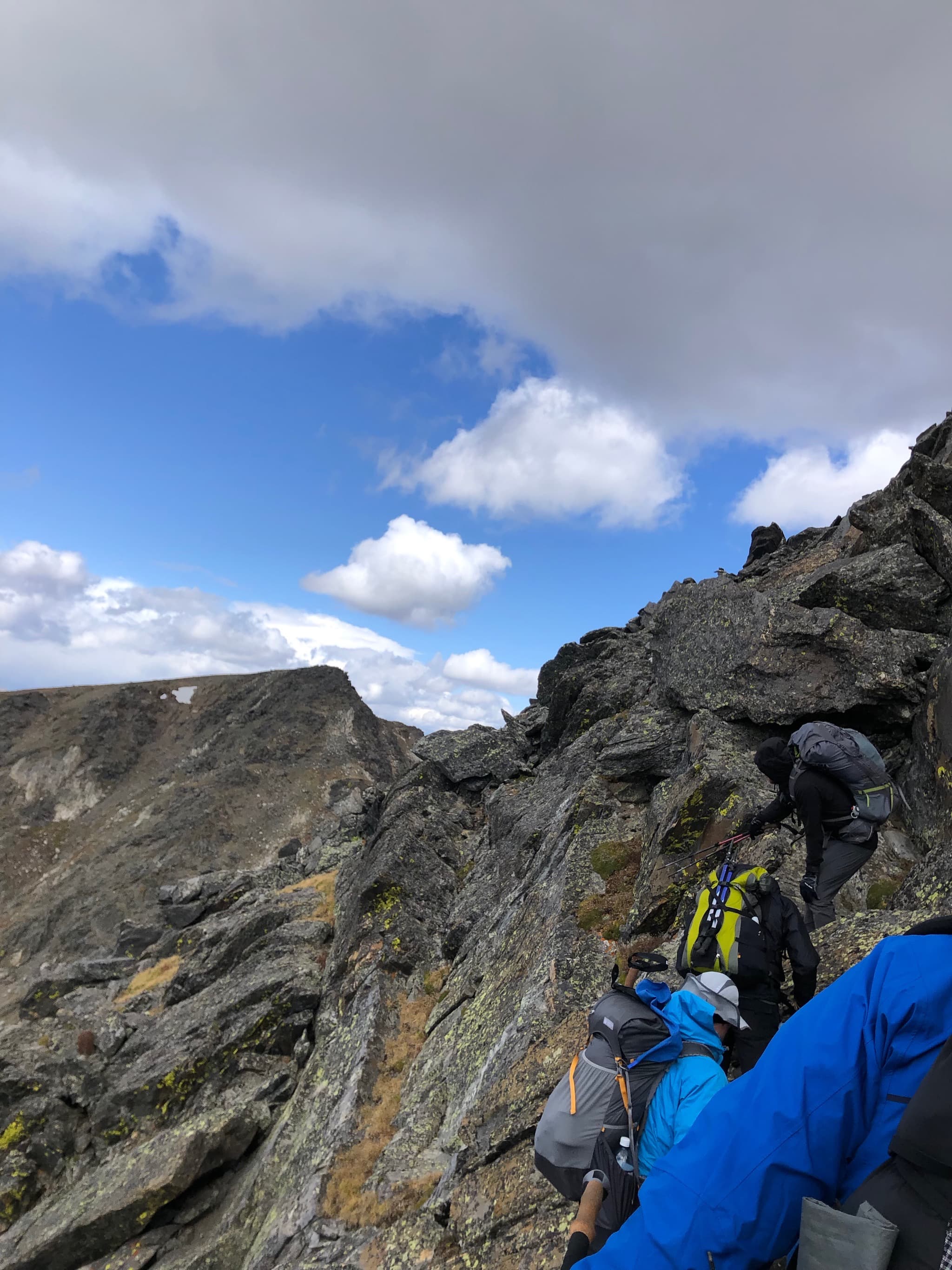 Backpackers on a steep, rocky, hill.