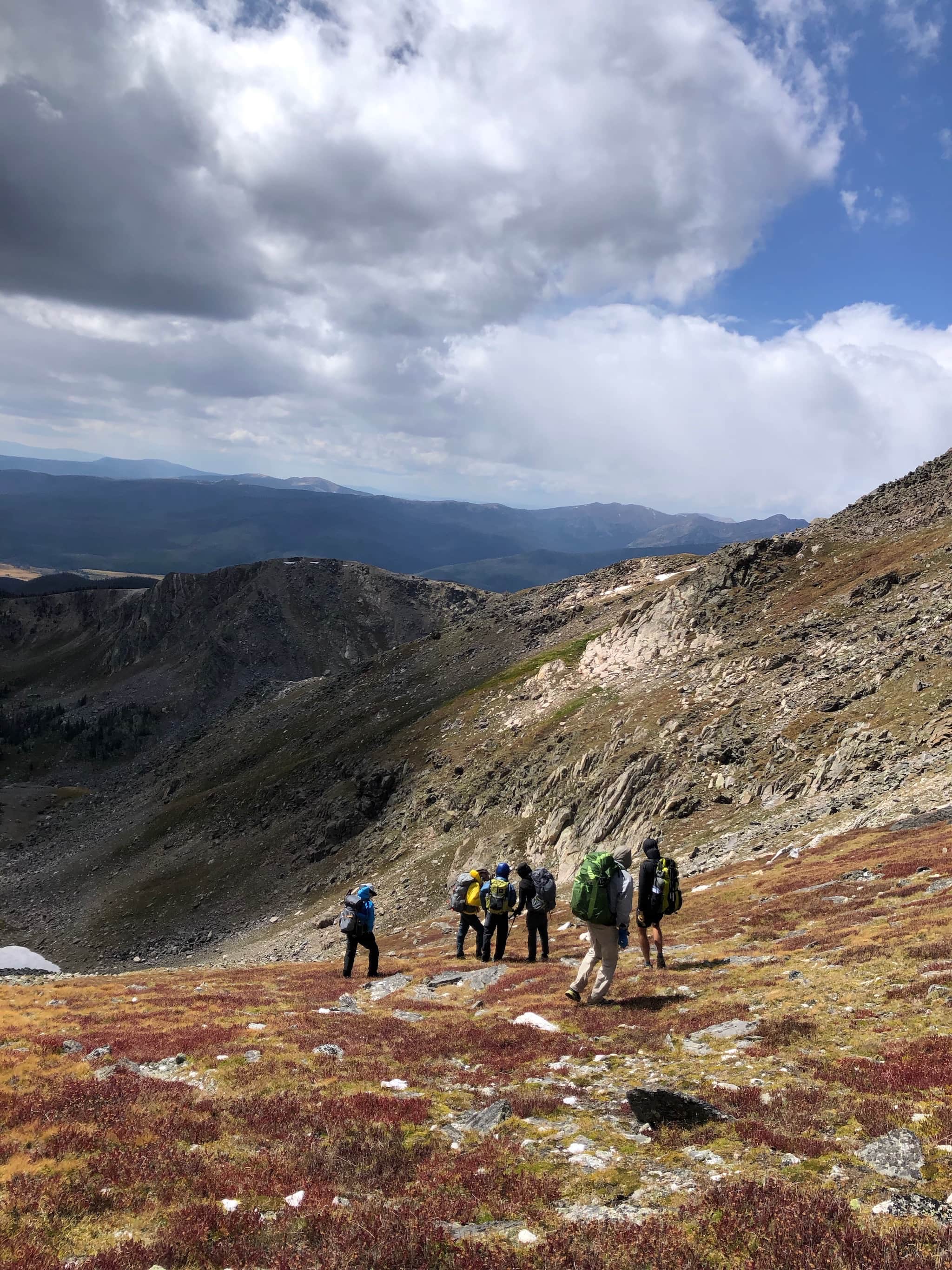 A group of hikers walking down steep tundra