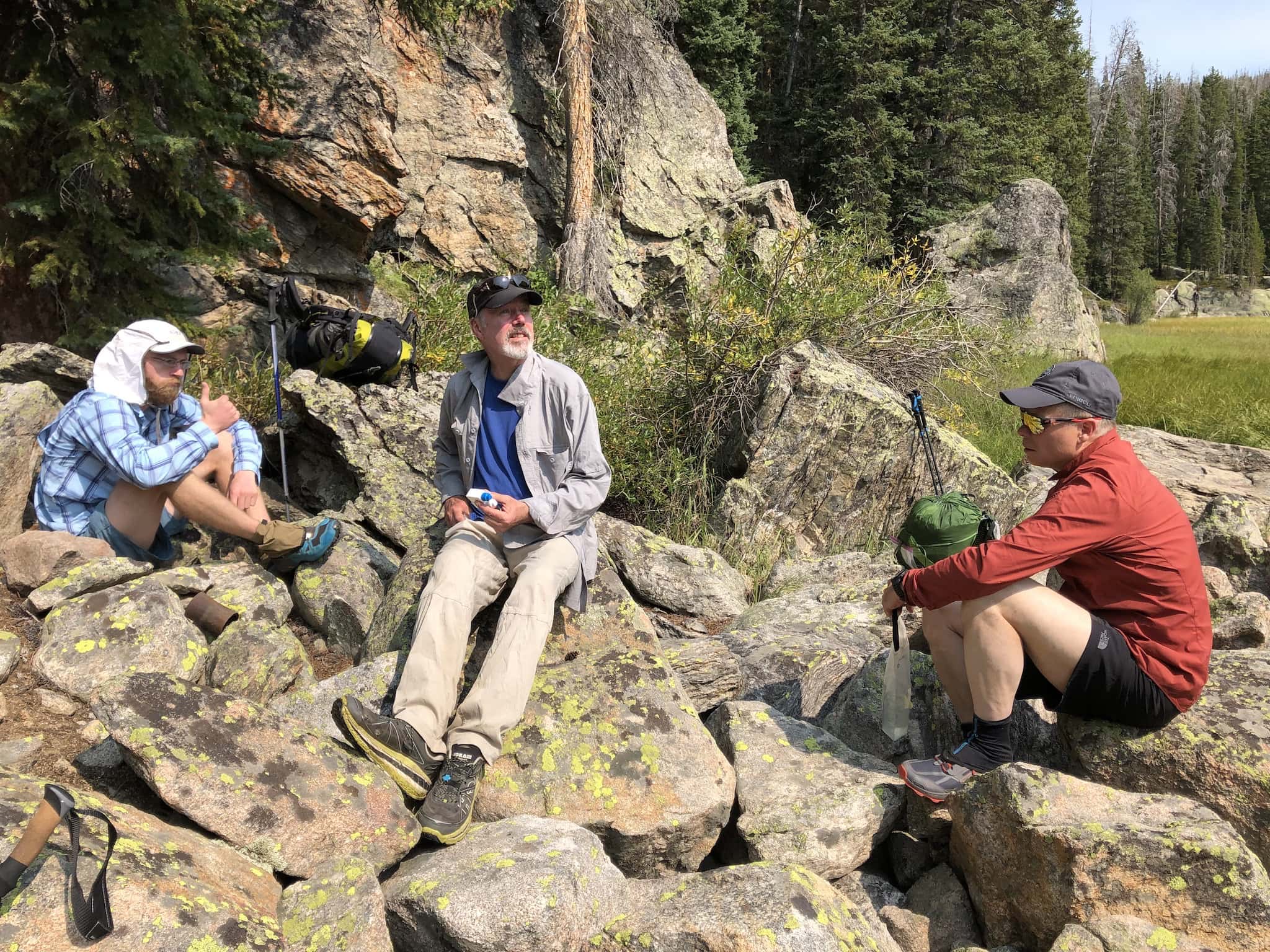 Three men sitting on rocks, 