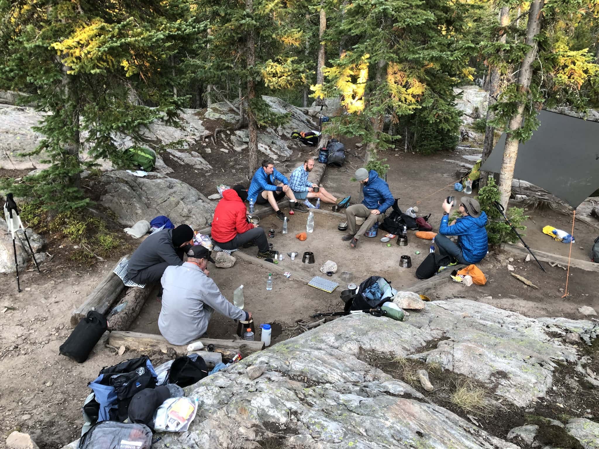 A group of backpackers sitting in a circle, making food on alcohol stoves.