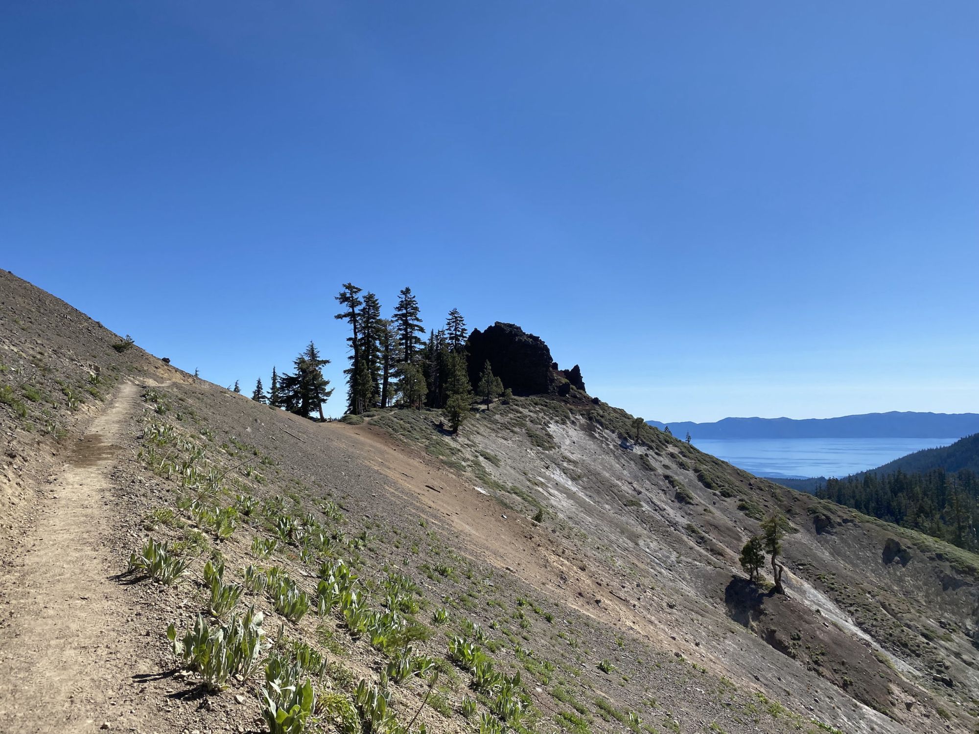 A trail leading up to a large rock formation above a lake