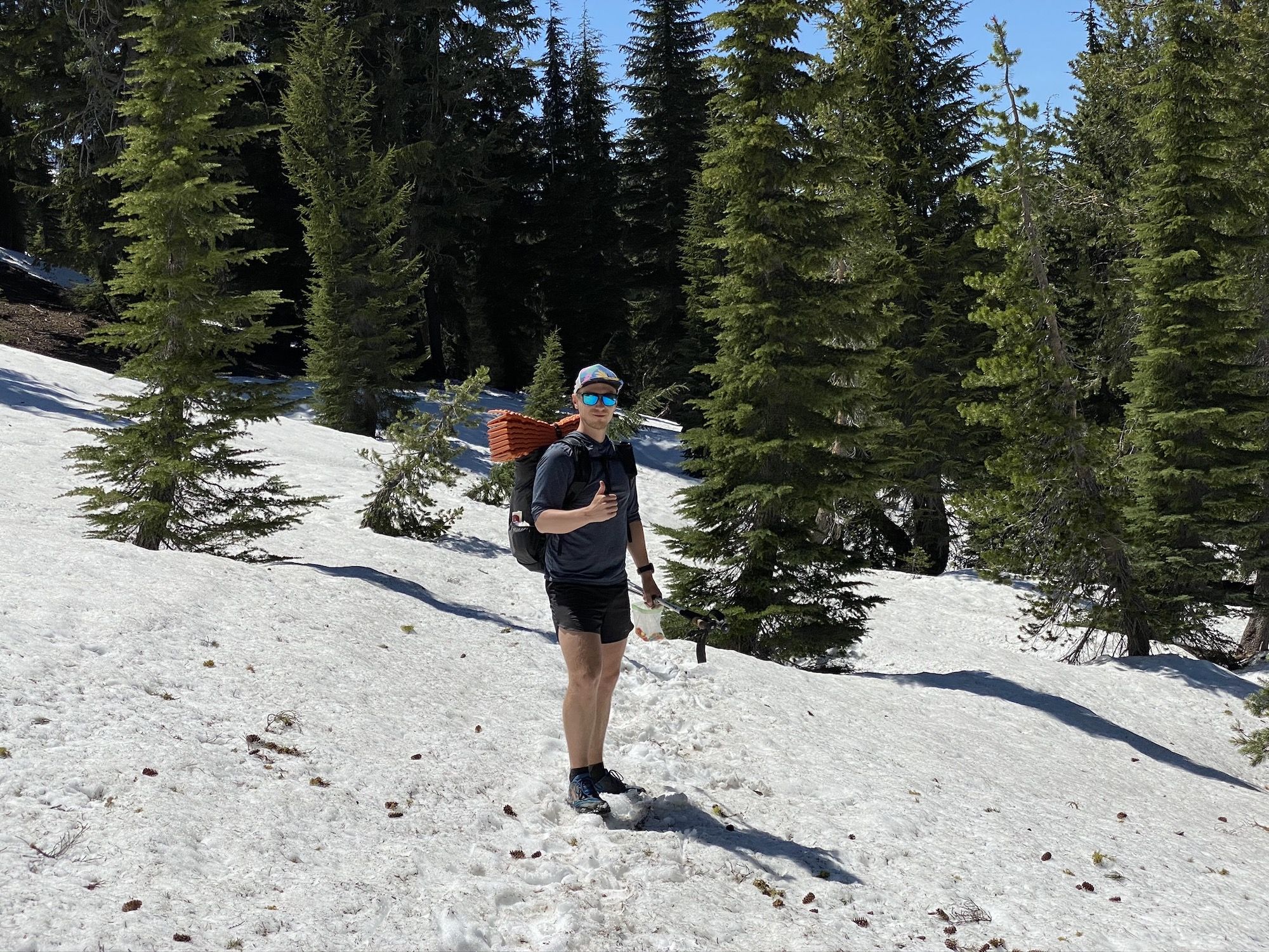 Man wearing shorts standing in a snowy forest.