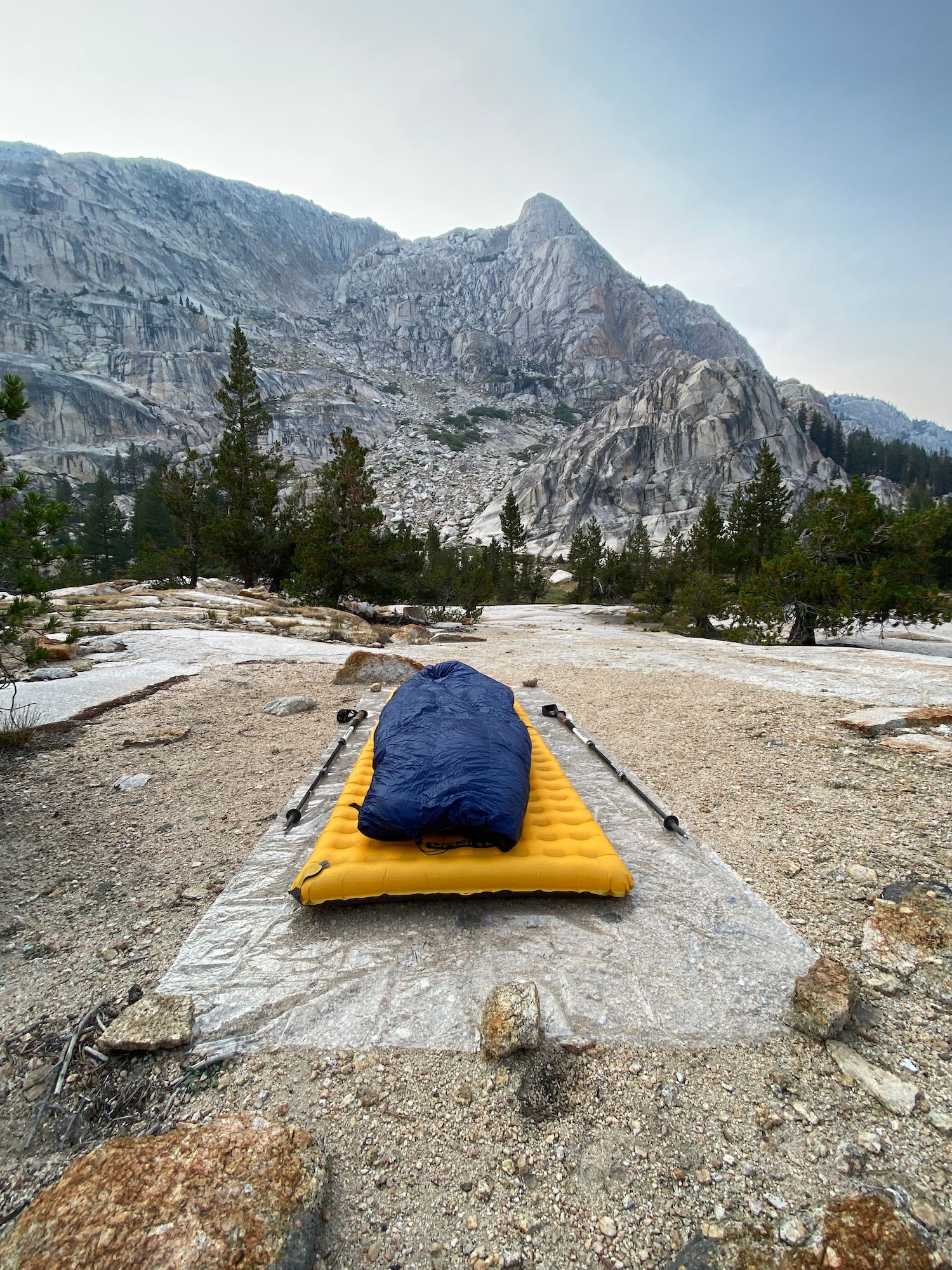 A sleeping bag on top of an air mattress with granite wall in the distance.