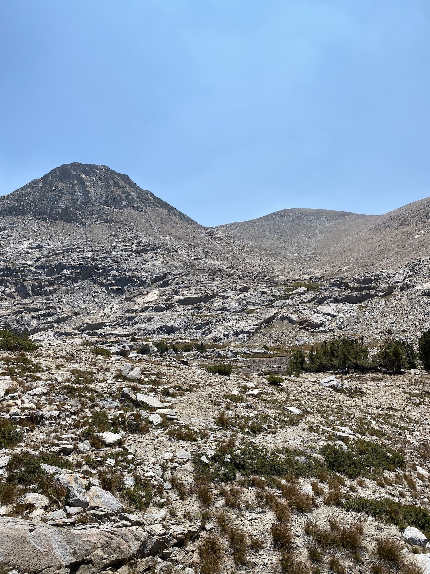A rocky mountain landscape with almost no vegetation. A mountain pass ahead.