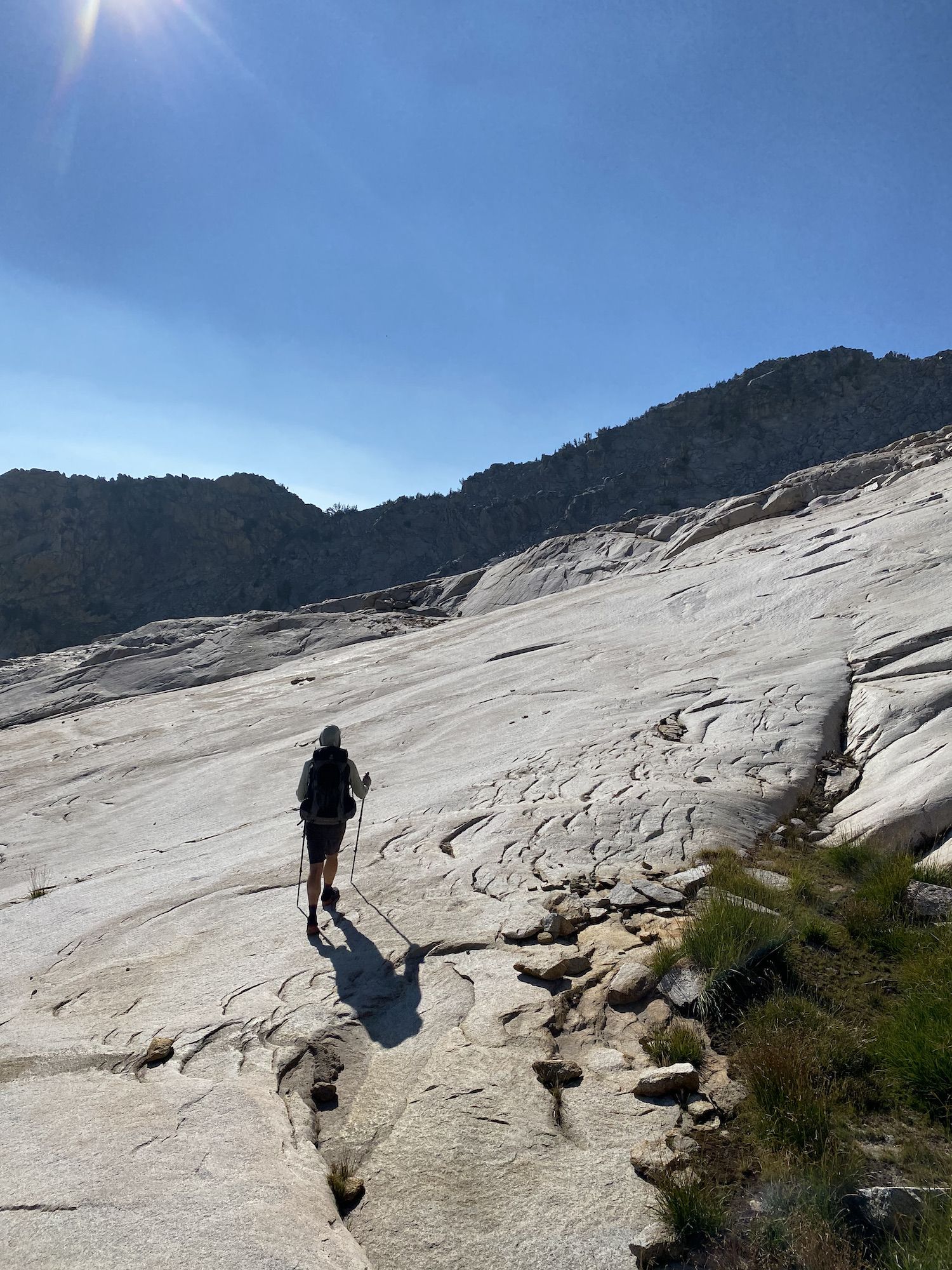 A backpacker walking on smooth granite.