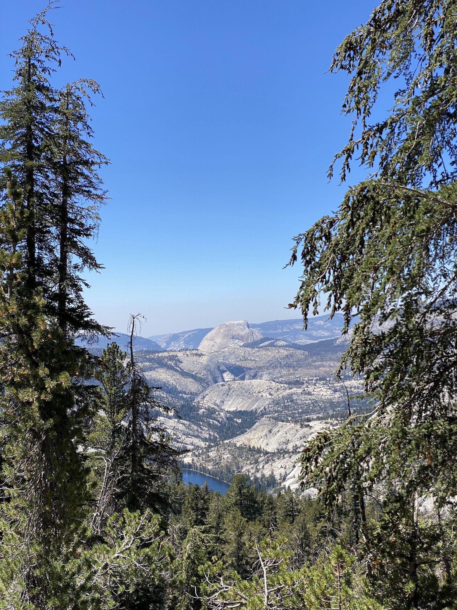 A river valley snaking through granite mountains, with Half Dome in the distance.