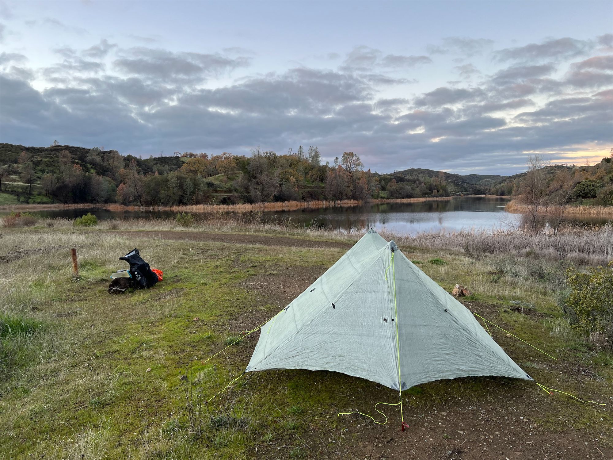 A tent in front of a lake.