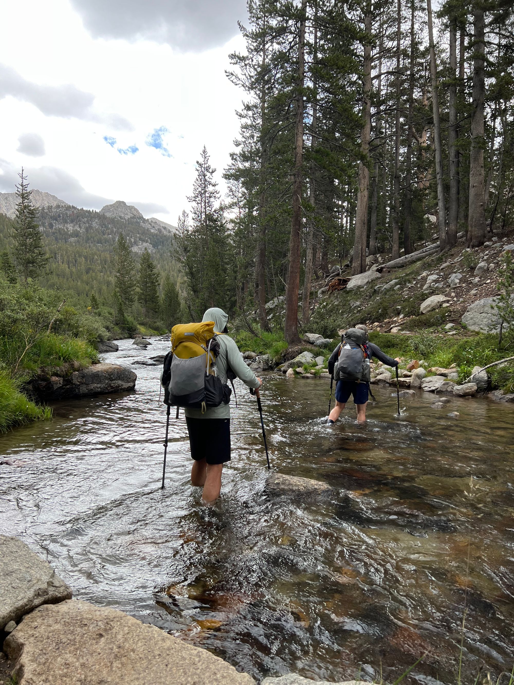 Two backpackers crossing a shin-deep creek.