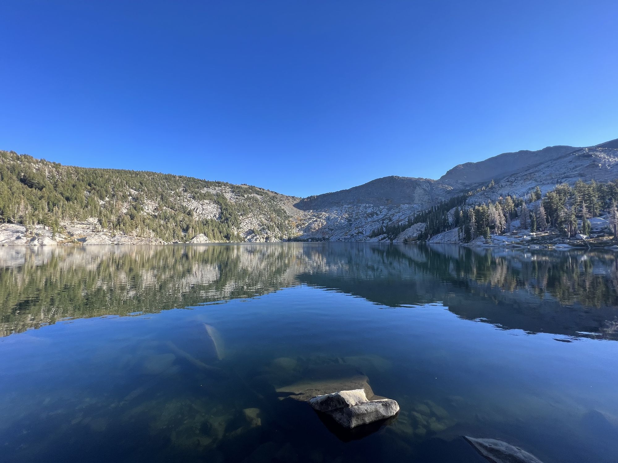 A still lake reflecting granite mountains.