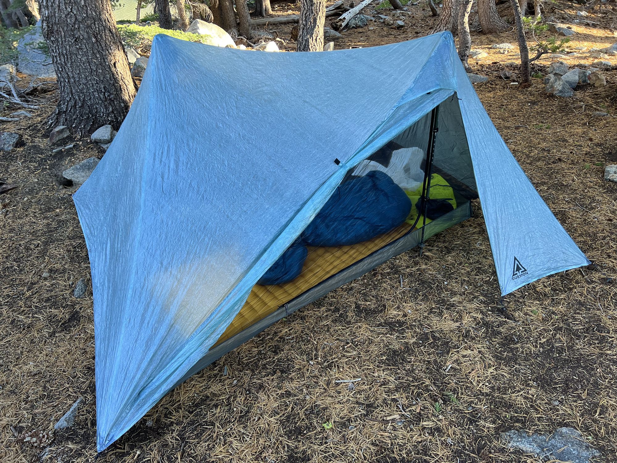 A blue-gray trekking pole tent with one door open.